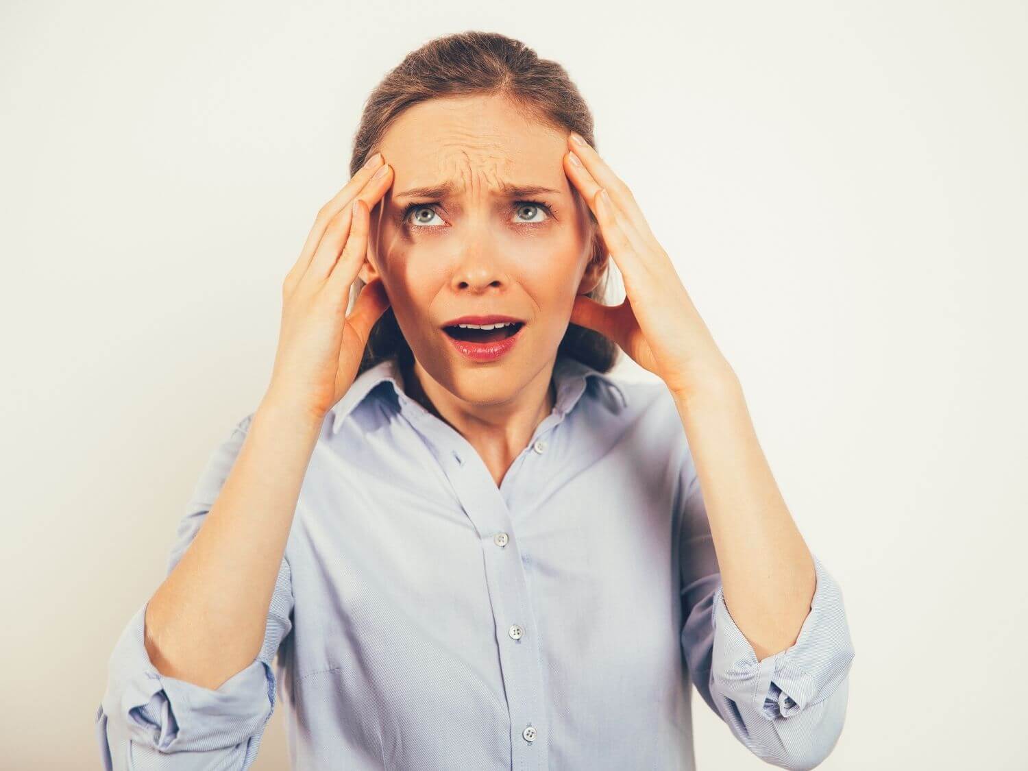 A lady holding her head and rolling her eyes