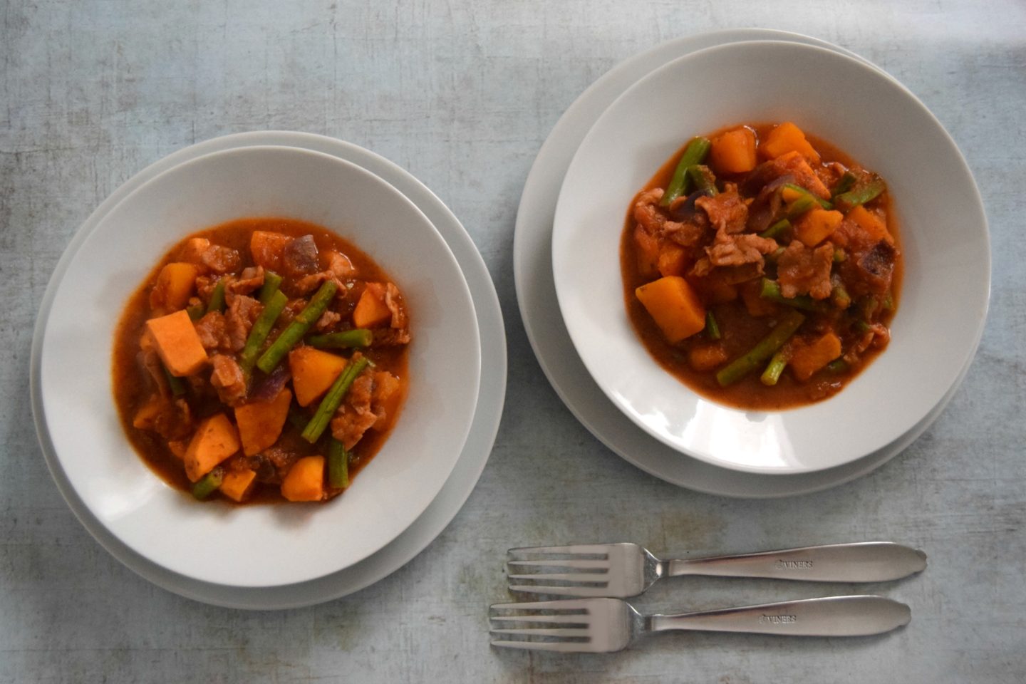 Two white bowls filled with Bacon, squash and sweet potato stew