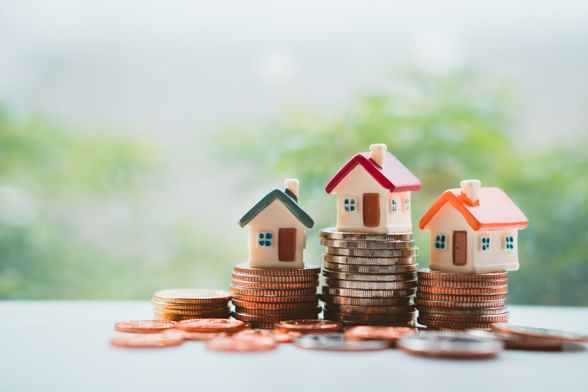 House prices. Model houses sitting on towers of coins.