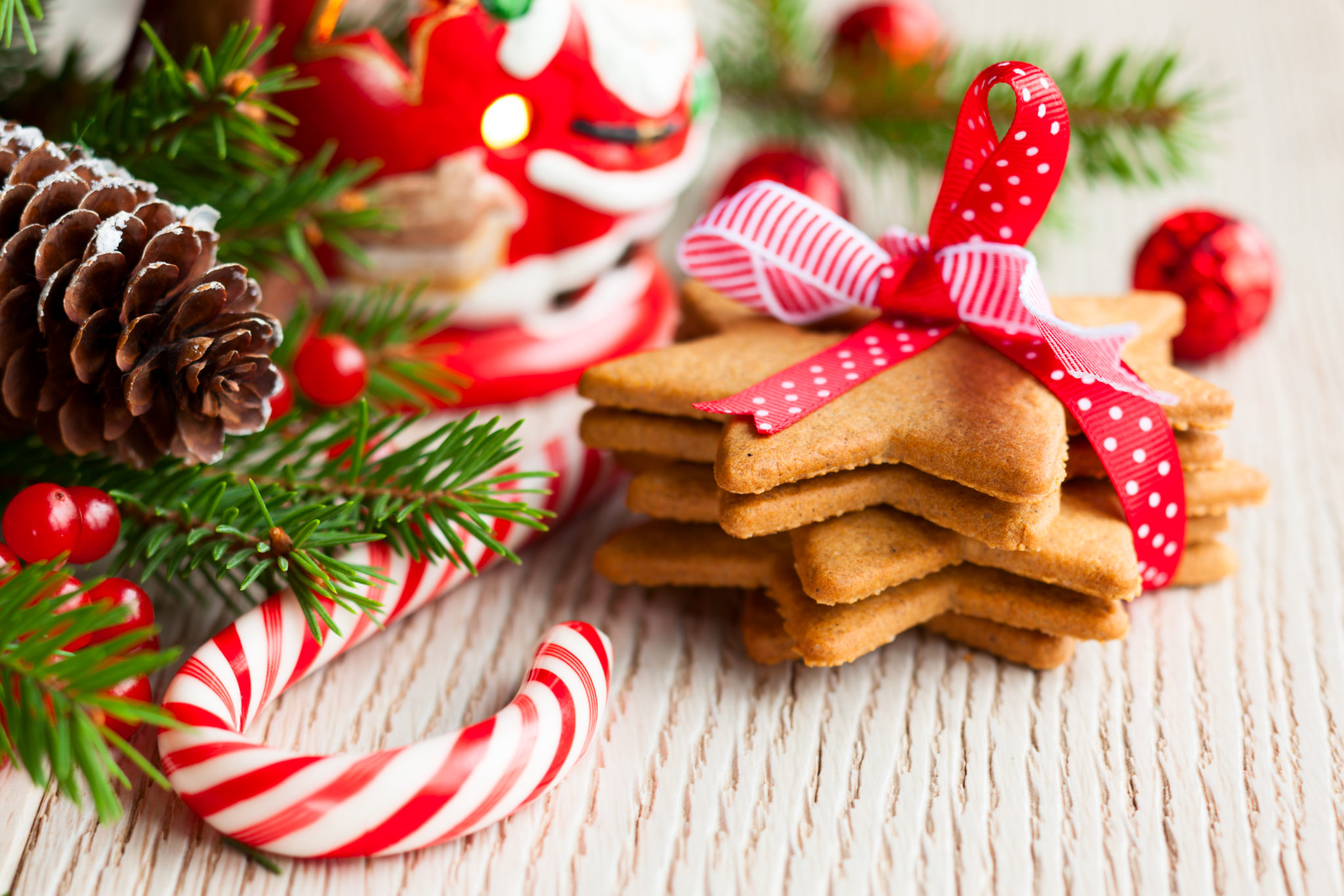 Christmas baking. A pile of star shaped biscuits wrapped with ribbon and a sprig of spruce and a candy.