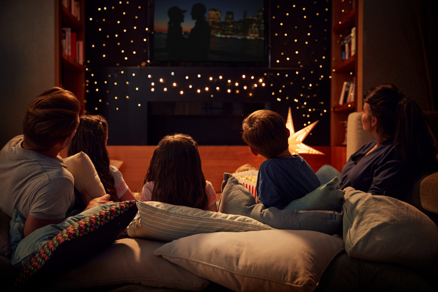 Family movie night. A family lying on cushions watching a movie together.