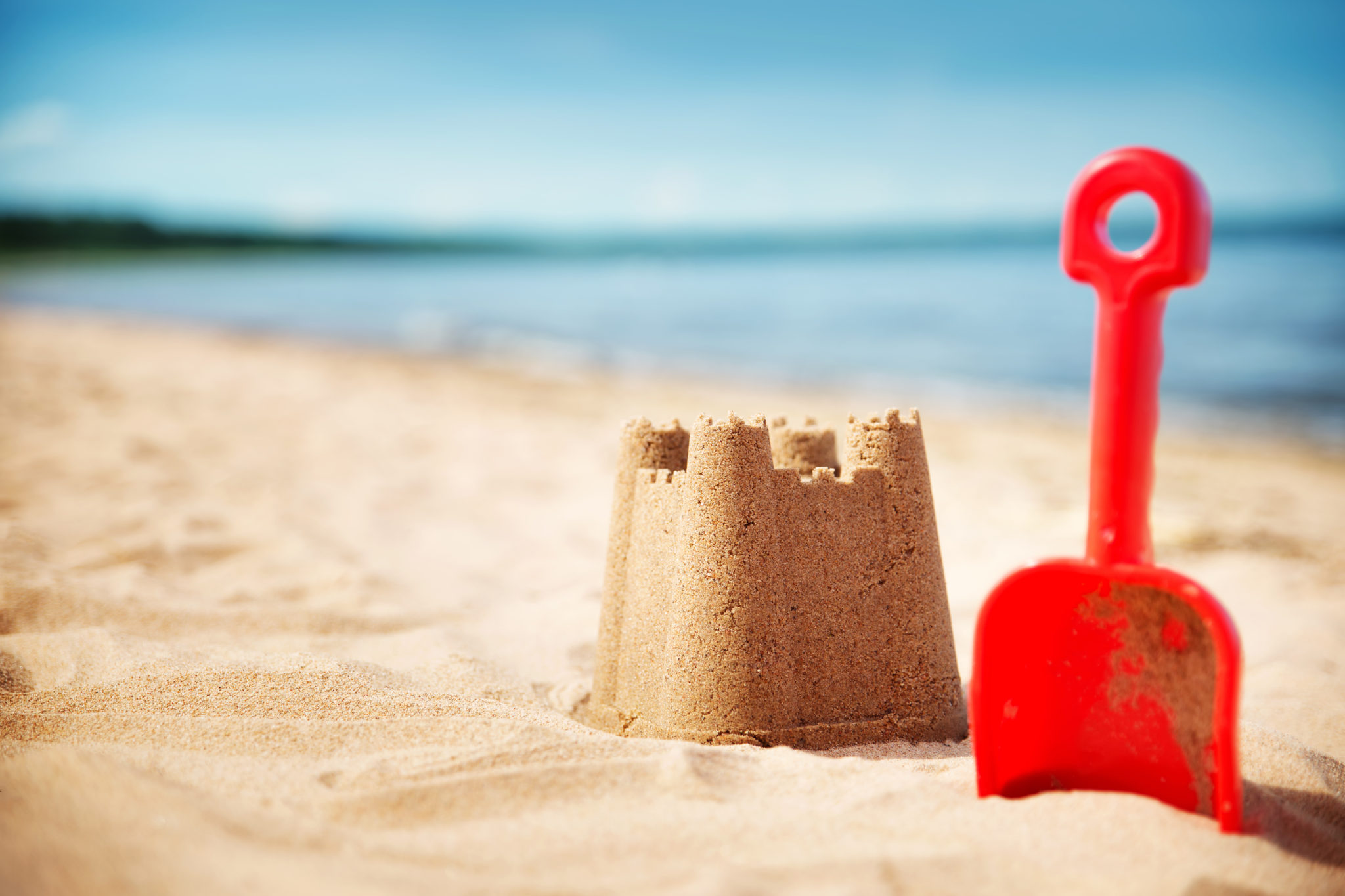 A sandcastle and spade on a beach