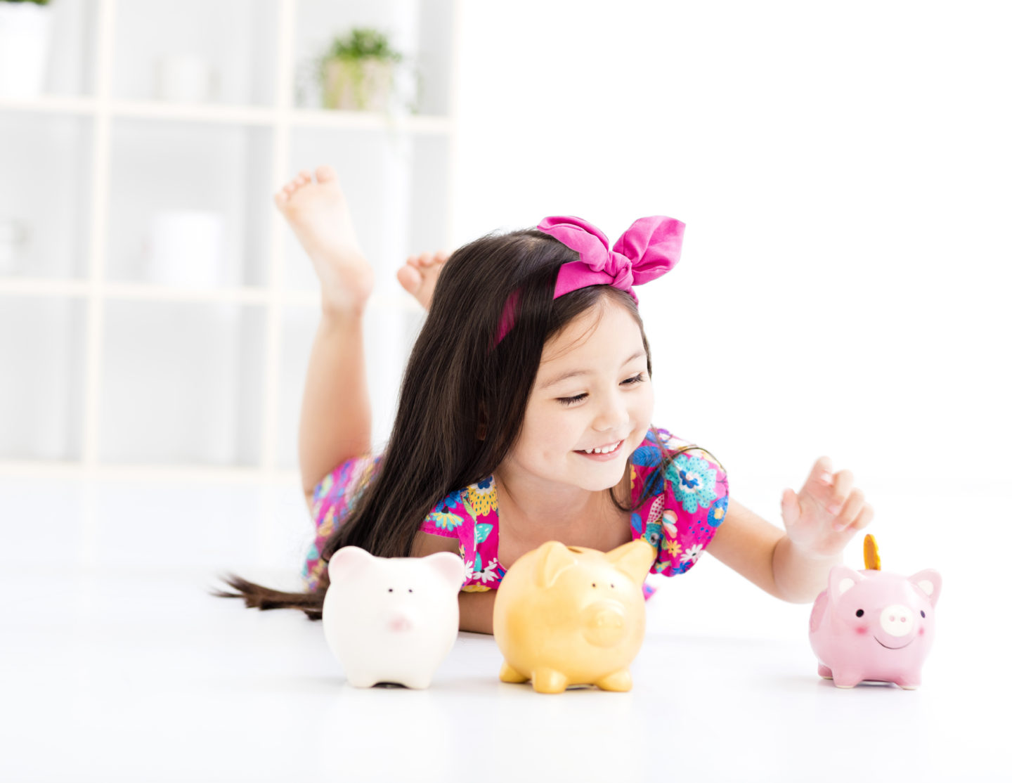 A little girl putting money in her piggy bank