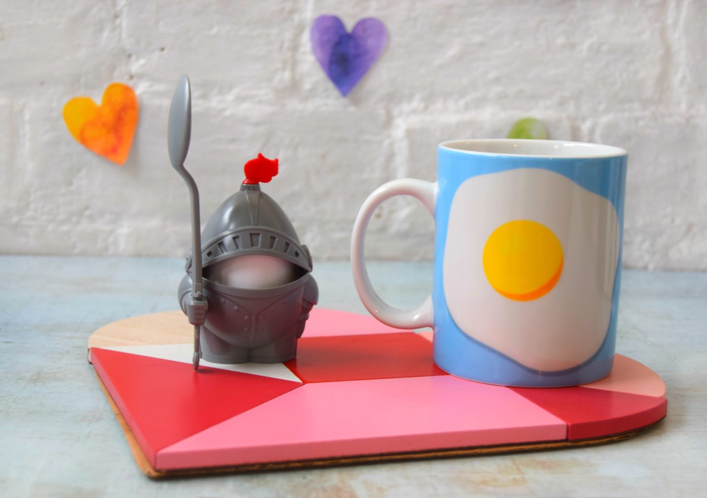 Breakfast in bed set. A heart coaster, a novelty knight egg cup and spoon and a blue mug with a fried egg on.