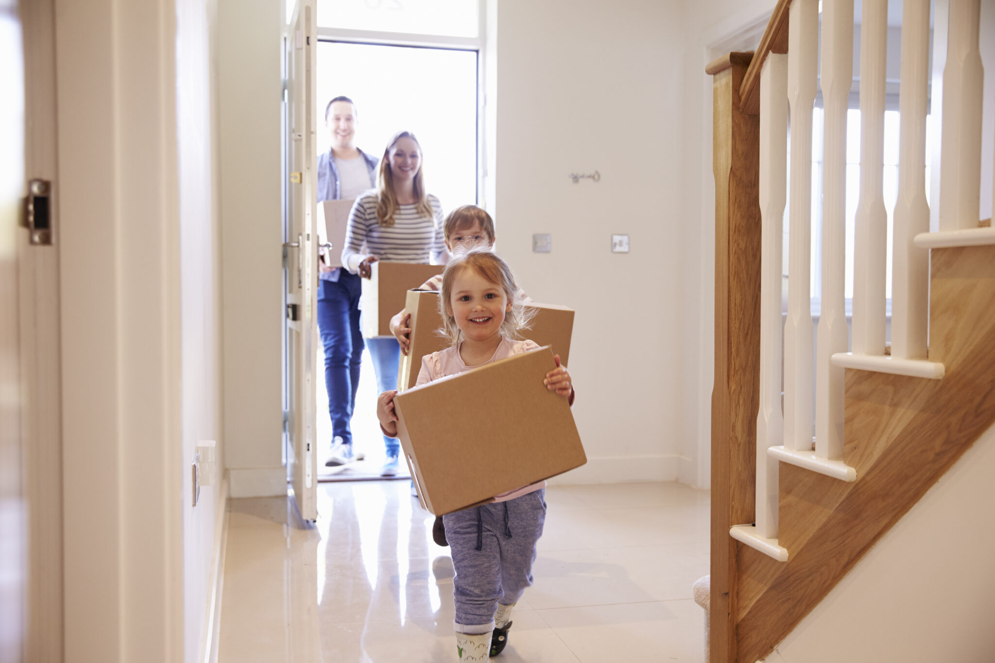 Moving house with kids. A family carrying boxes into their new home.
