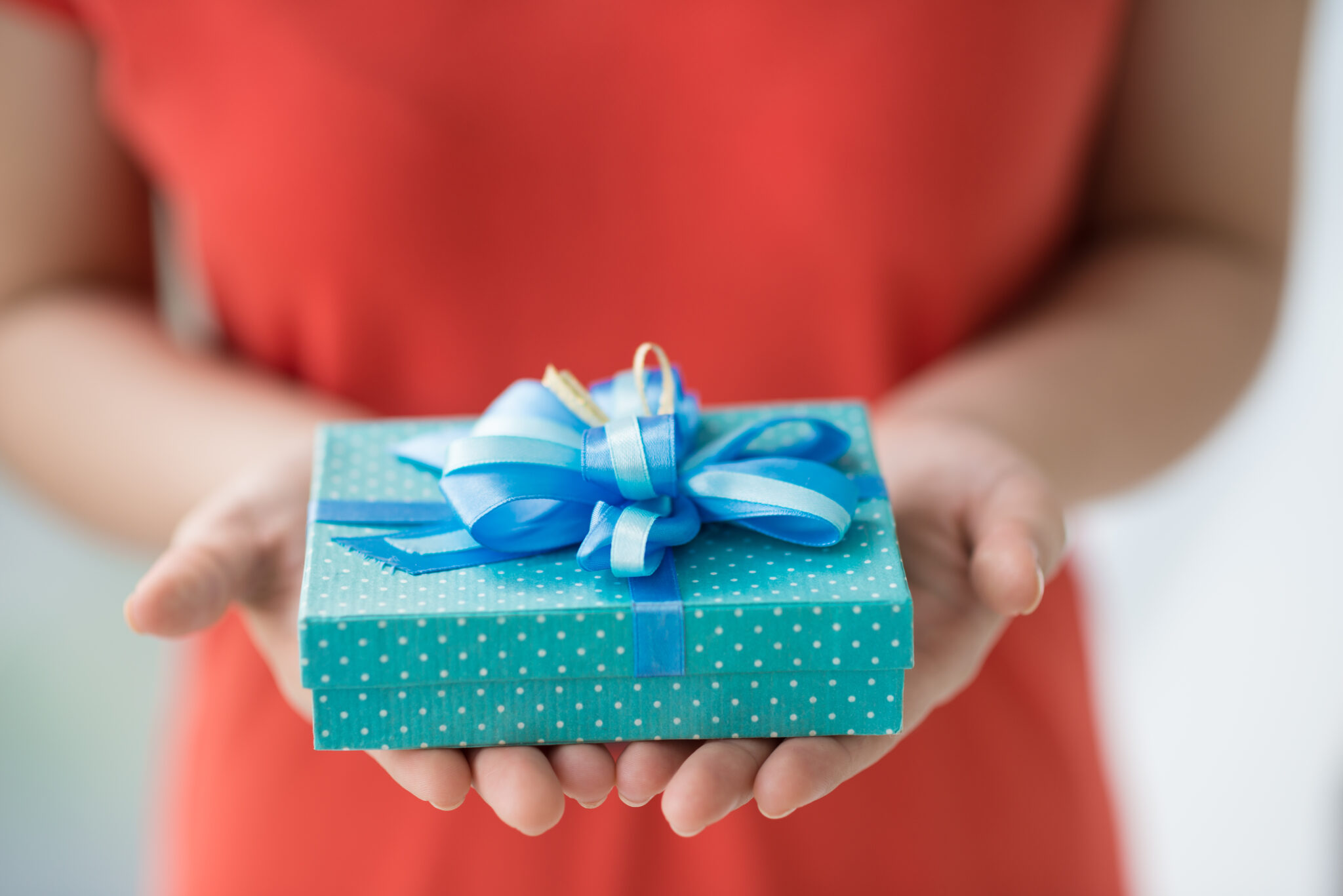 Personalised gifts ideas. A lady holding a pretty blue polka dot gift box with ribbon