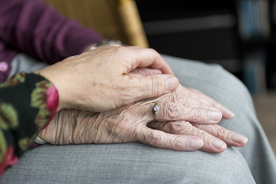 caring for the elderly. Two people with one hand on top of the other.