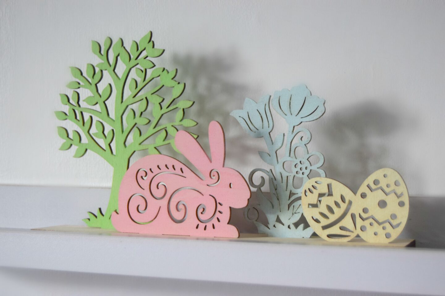 Wooden Easter scene with a tree, rabbit, flowers and eggs. Painted in pastel shades. Easter craft.