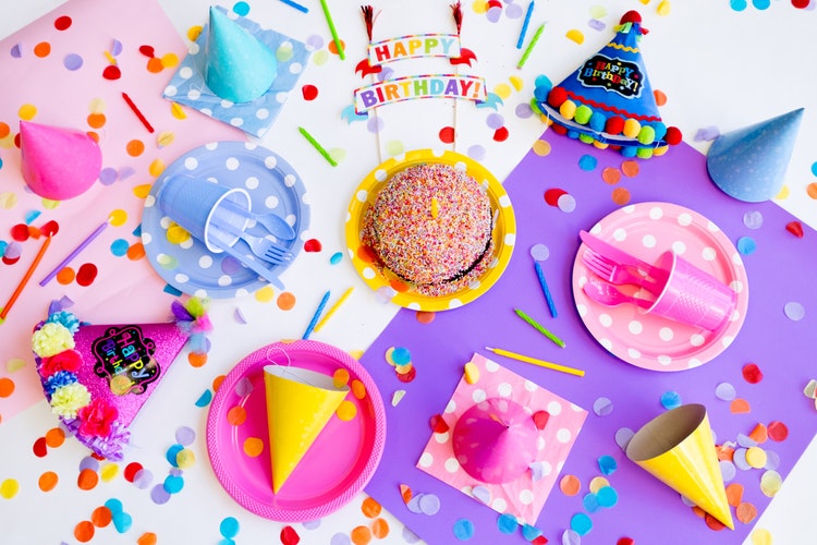 Birthday gifts for 9-year-olds. A birthday party table with decorations, pink and blue paper plates and a birthday cake.