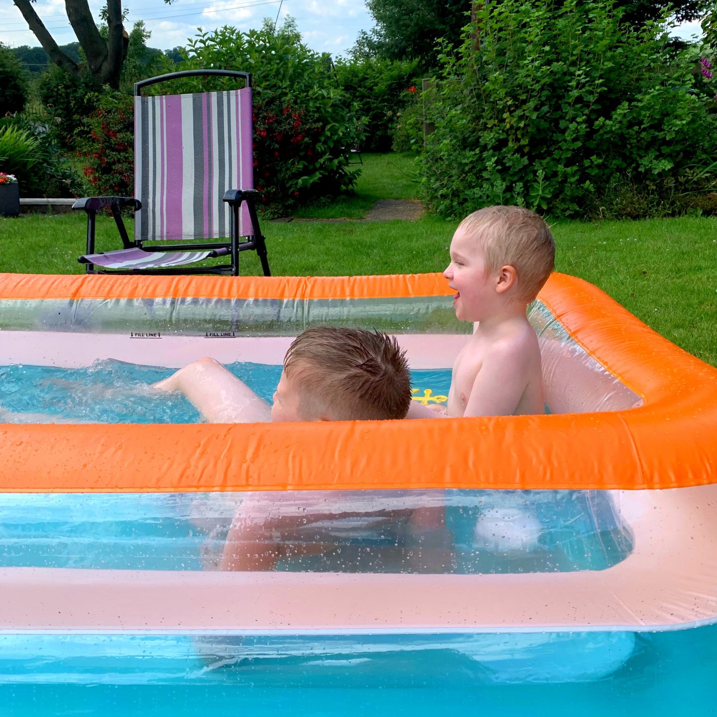 Children playing in the orange and blue paddling pool