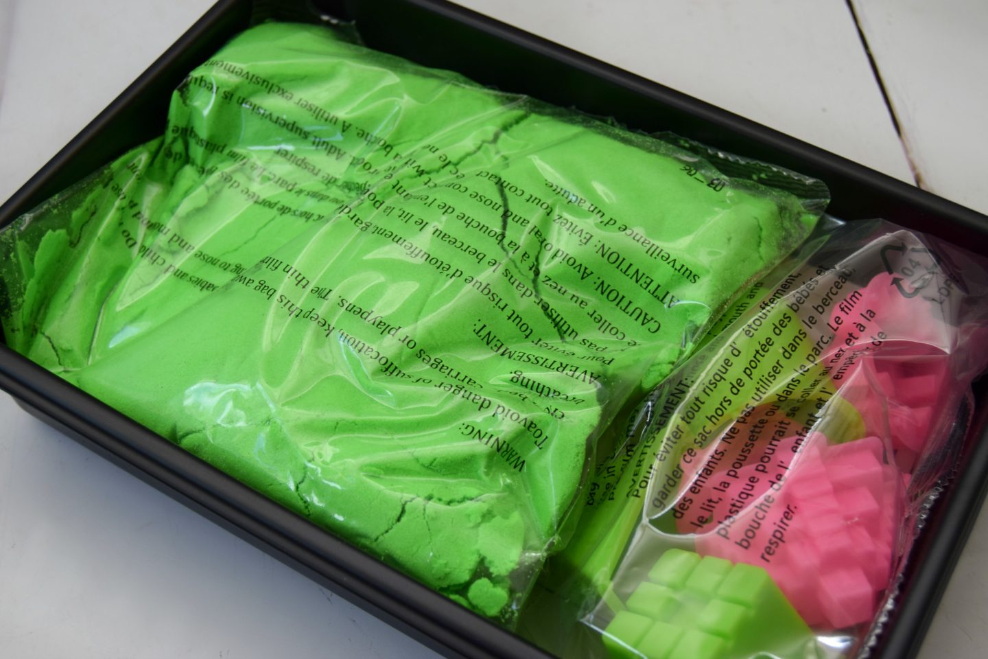 Neon green kinetic sand in tray