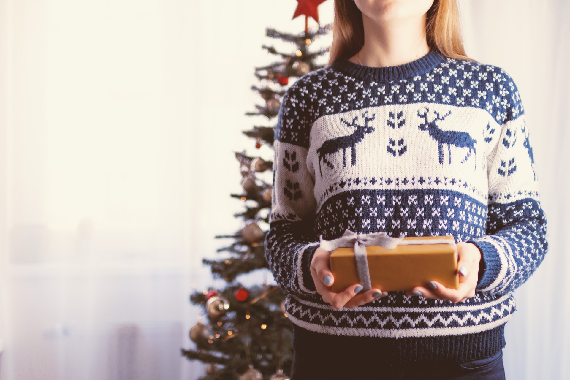 Random acts of kindness. A lady giving a gift whilst wearing her Christmas jumper