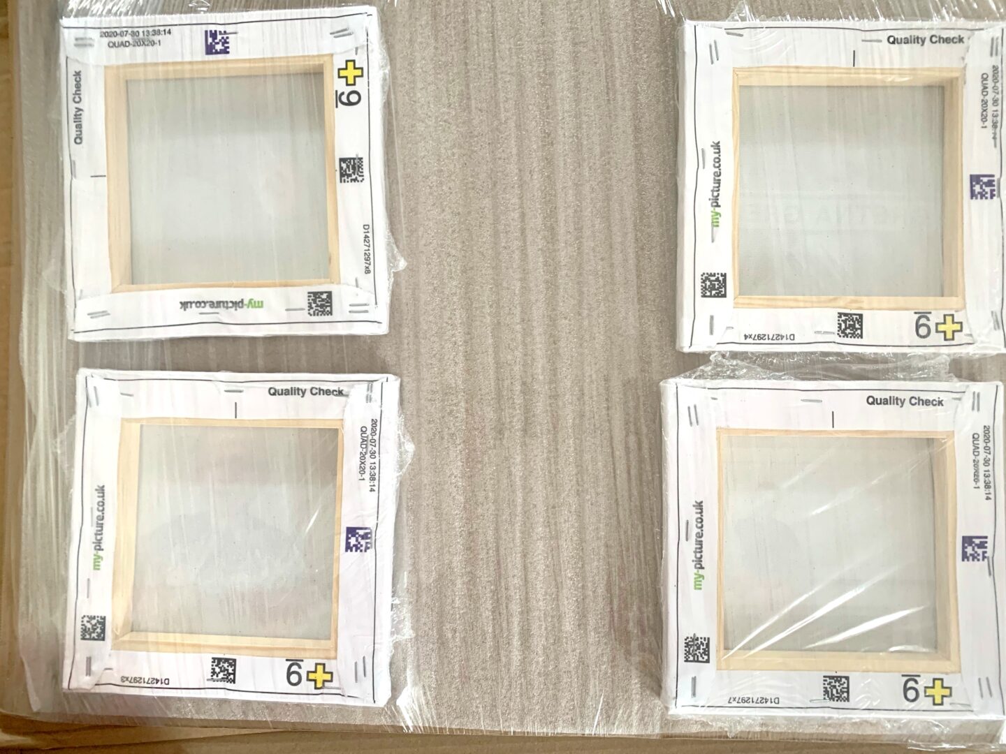 A photo of 4 canvases in their cardboard and shrink-wrap packaging.