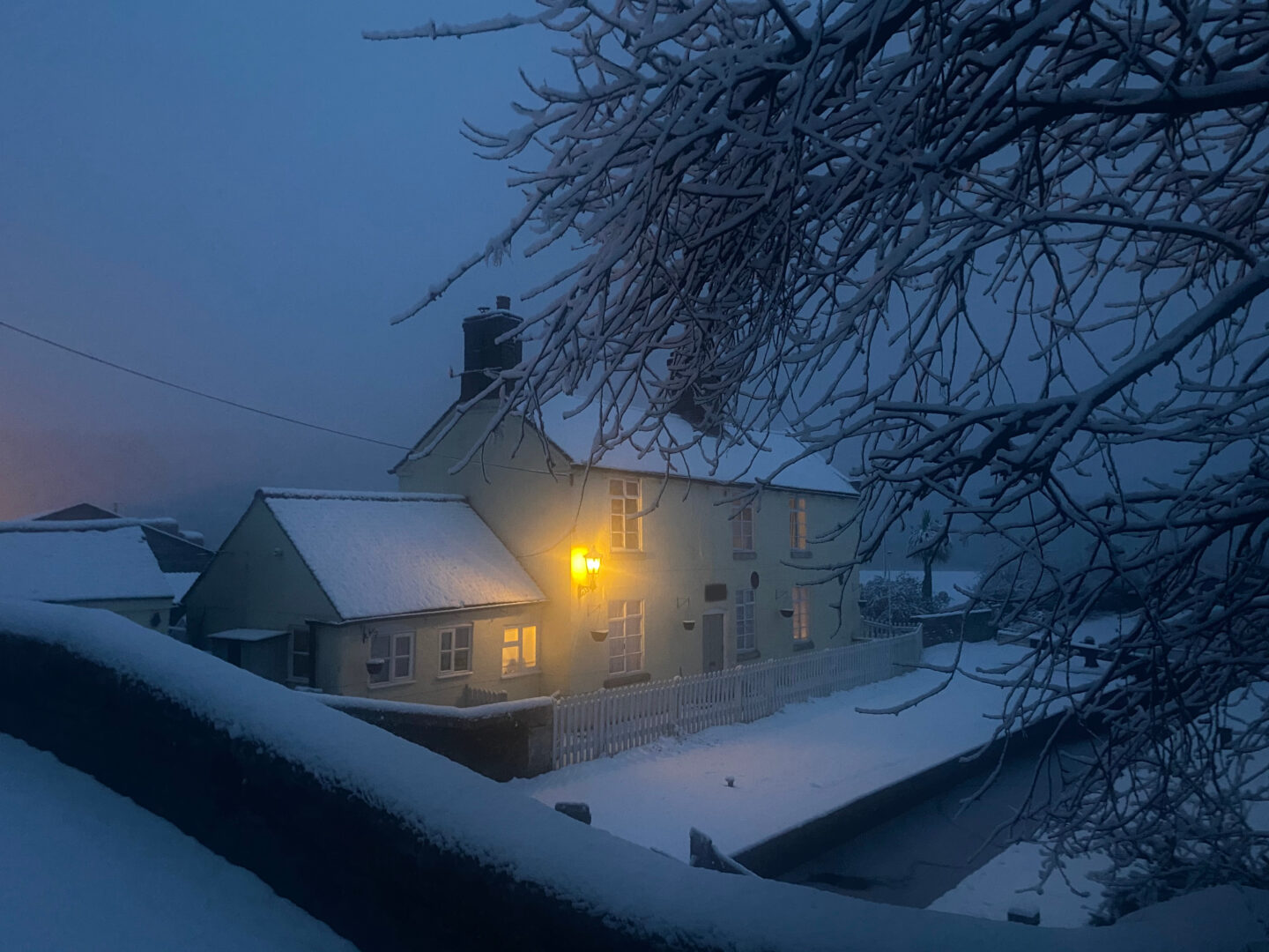 Snowy scenery surrounding a canal side cottage