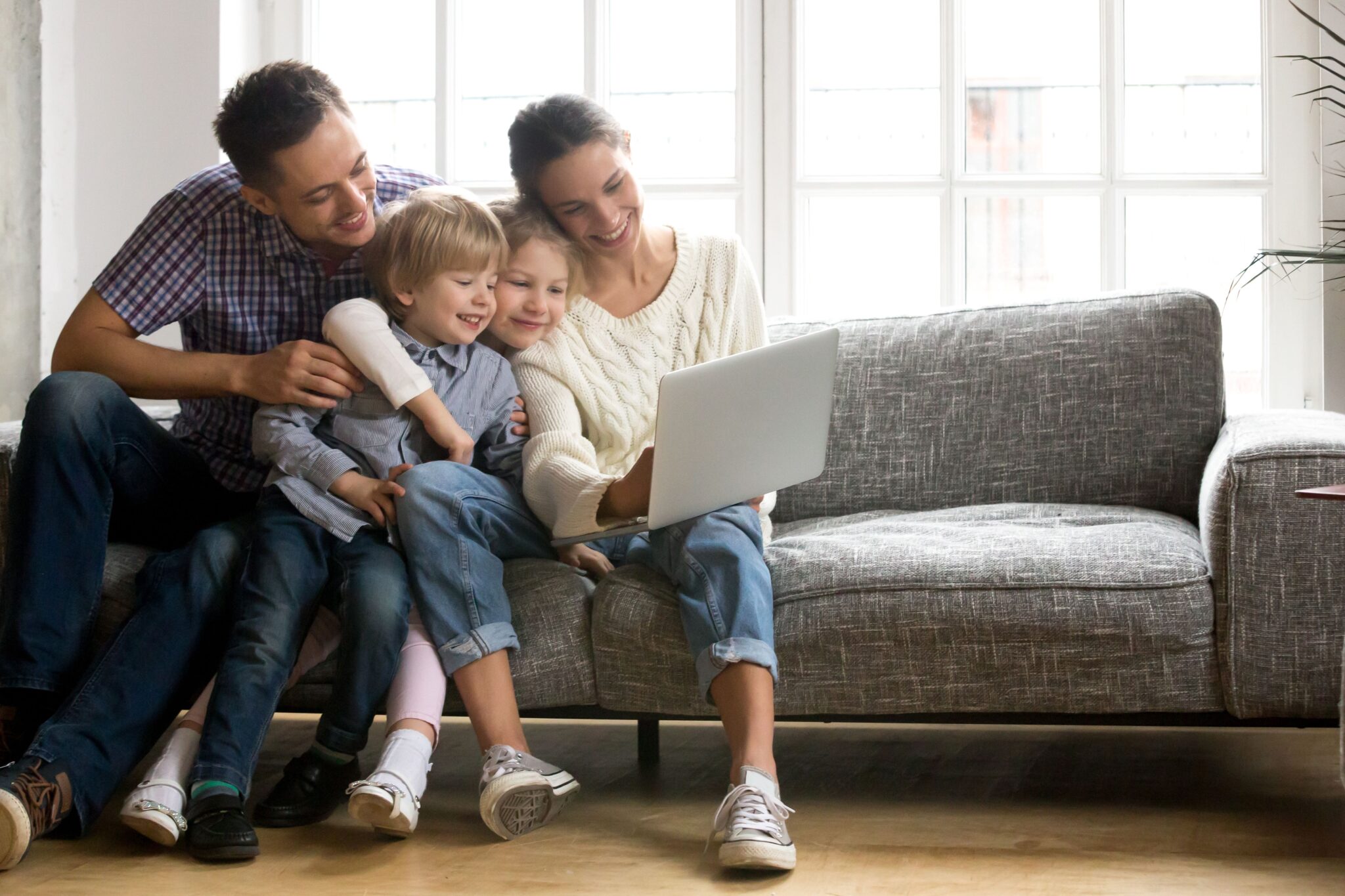 Family sitting together on the sofa looking at a laptop.