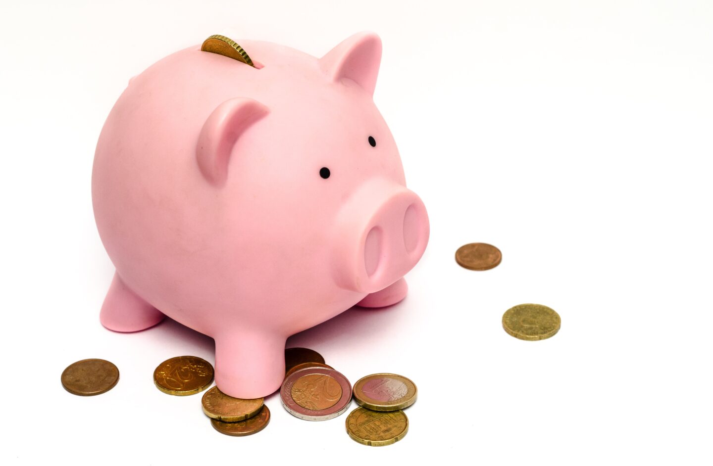 A plump pink piggy bank surrounded by coins