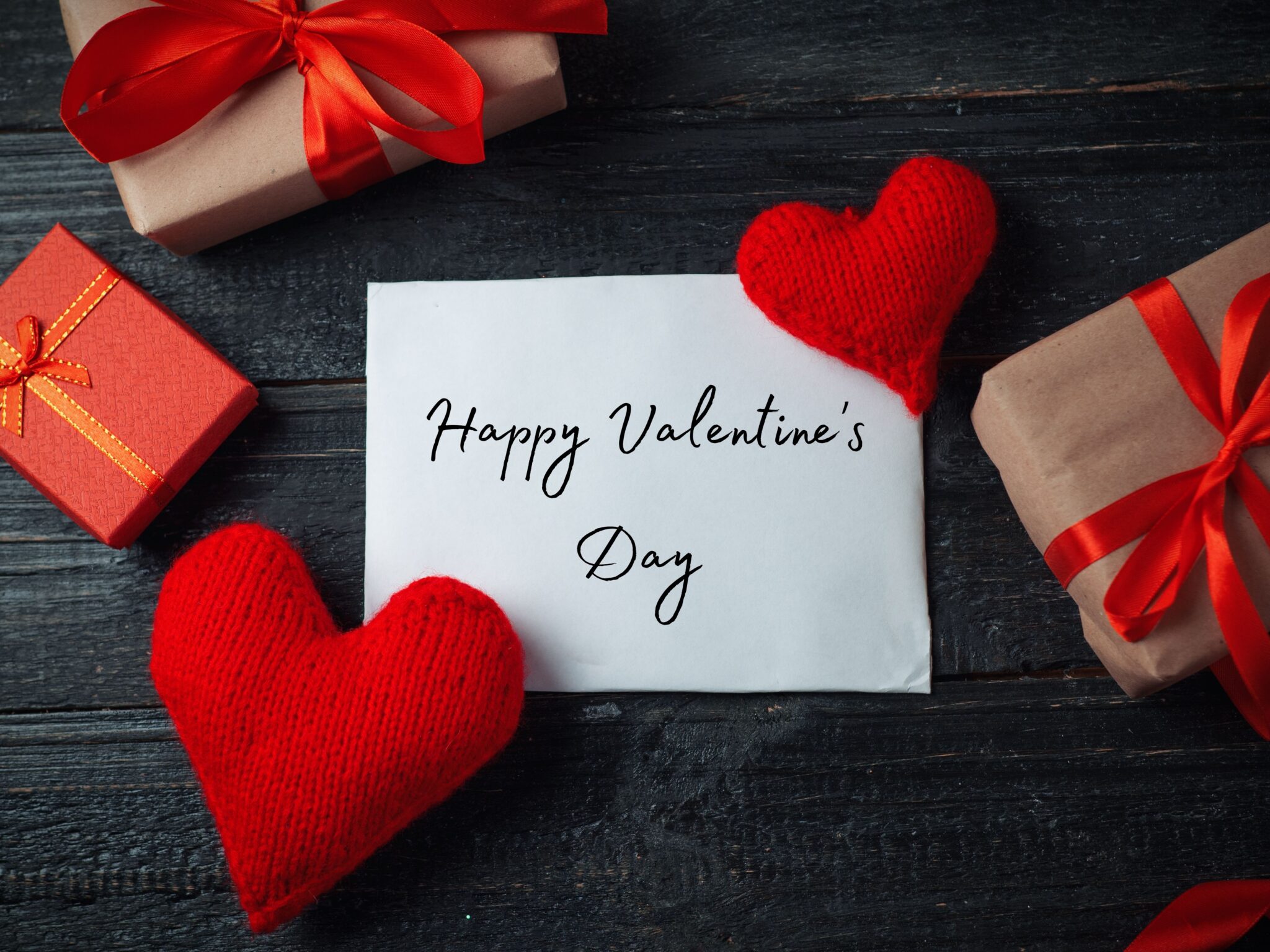 A Valentine's Day inspired flatlay with wool hearts, mini parcels wrapped in brown craft paper and a Valentine's Day Card.