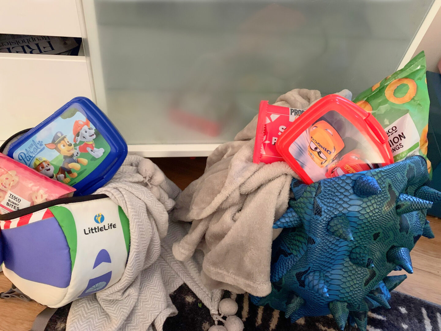 kids backpacks filled with treats and a blanket for camping indoors
