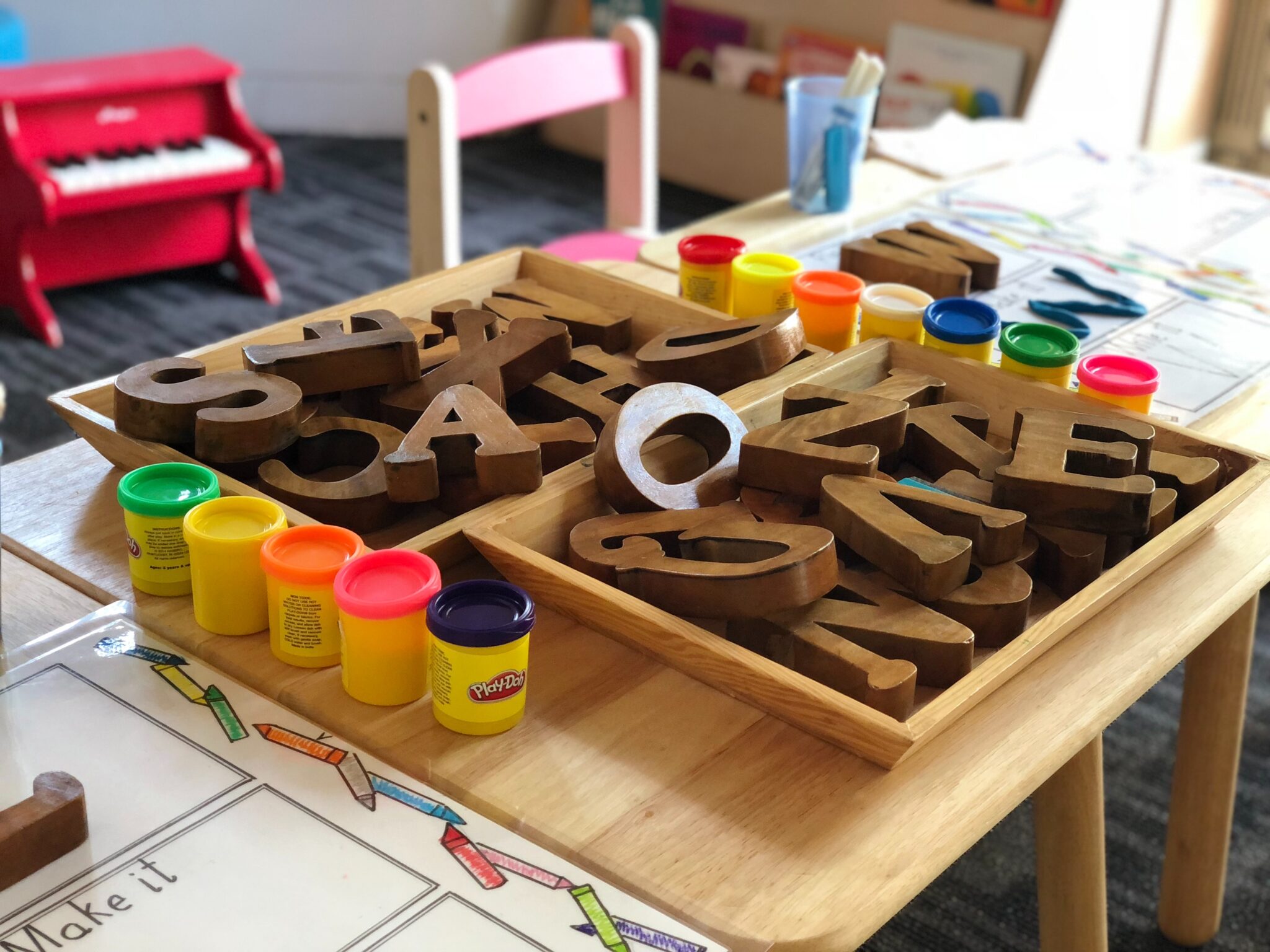 A nursery school table with playdoh and learning accessories.