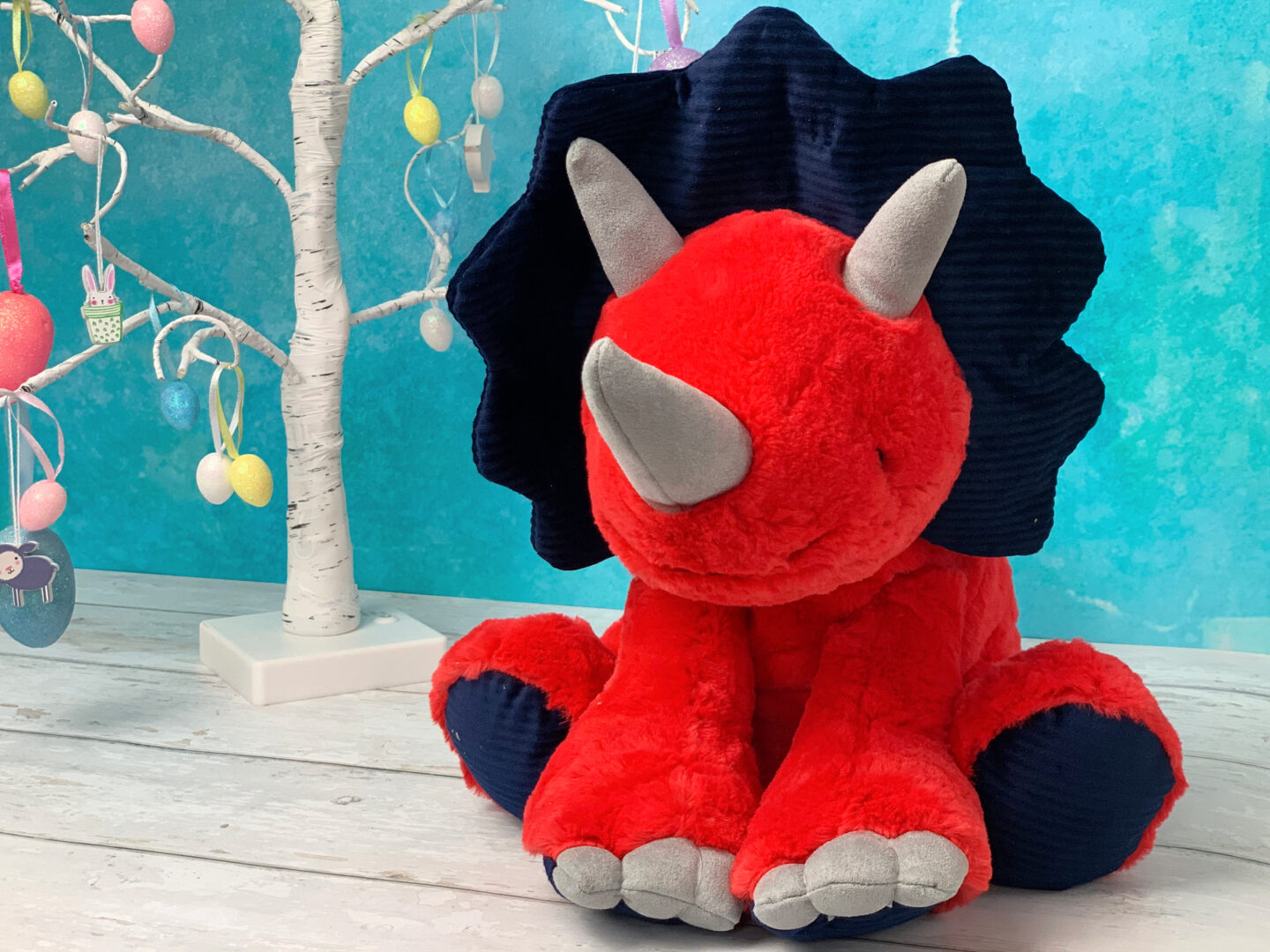 A colourful red and blue dinosaur soft toy