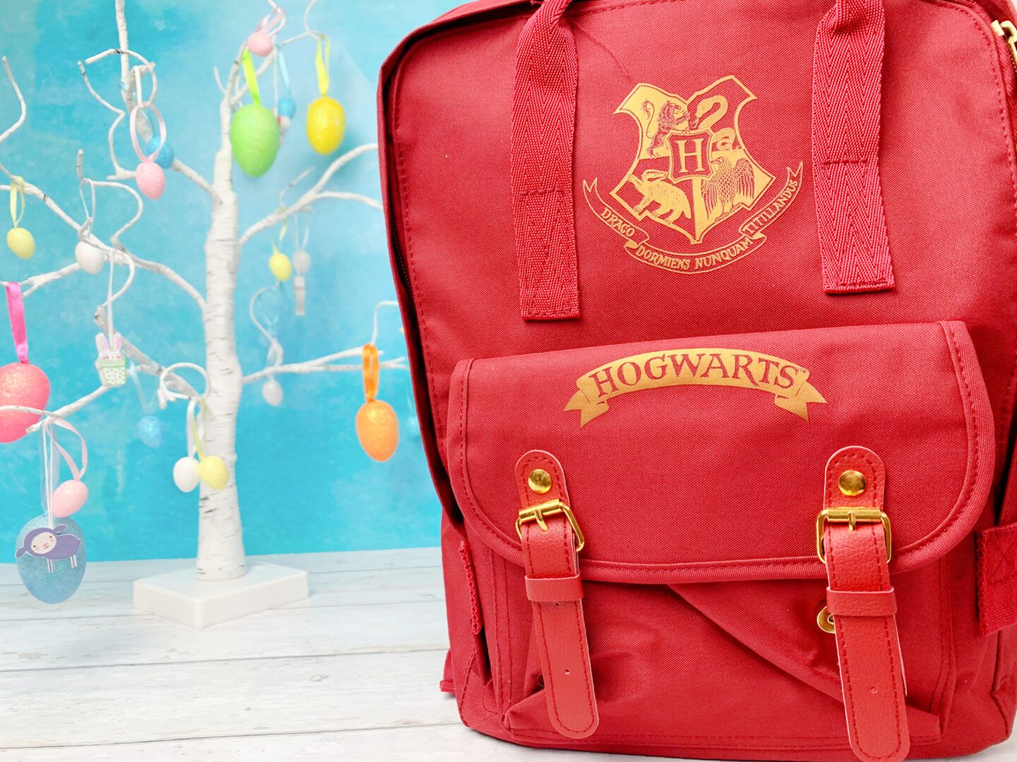 A red Harry Potter backpack with the gold Hogwarts crest on the front.