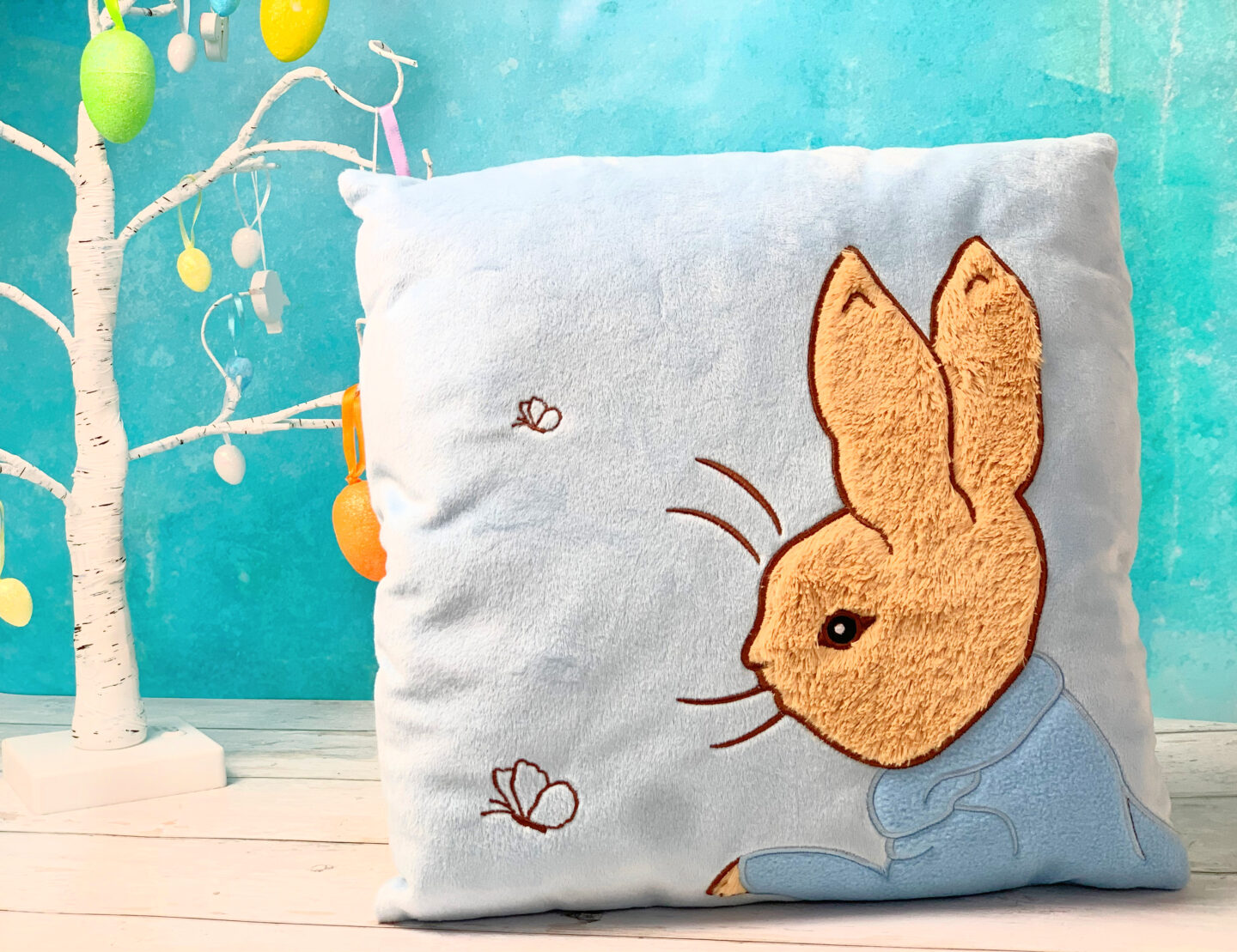 A soft powder blue kids cushion featuring Peter Rabbit