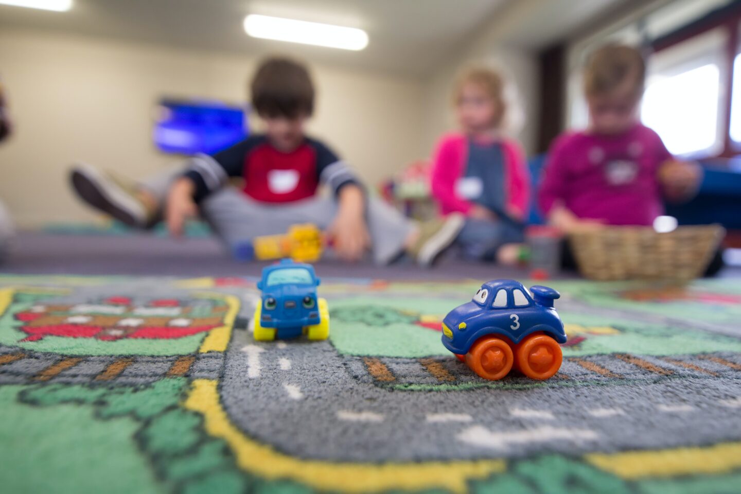 Children playing with toy cars on a road themed mat