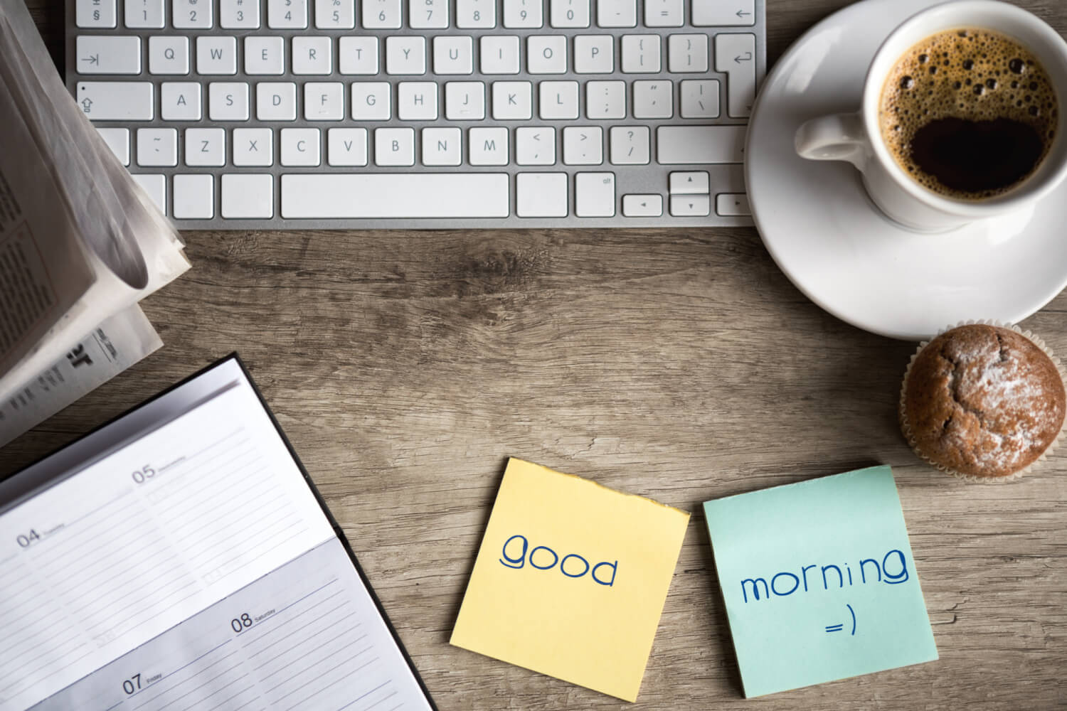 A bloggers desk with a keyboard, cup of tea, a diary and sticky notes with the words "Good morning".