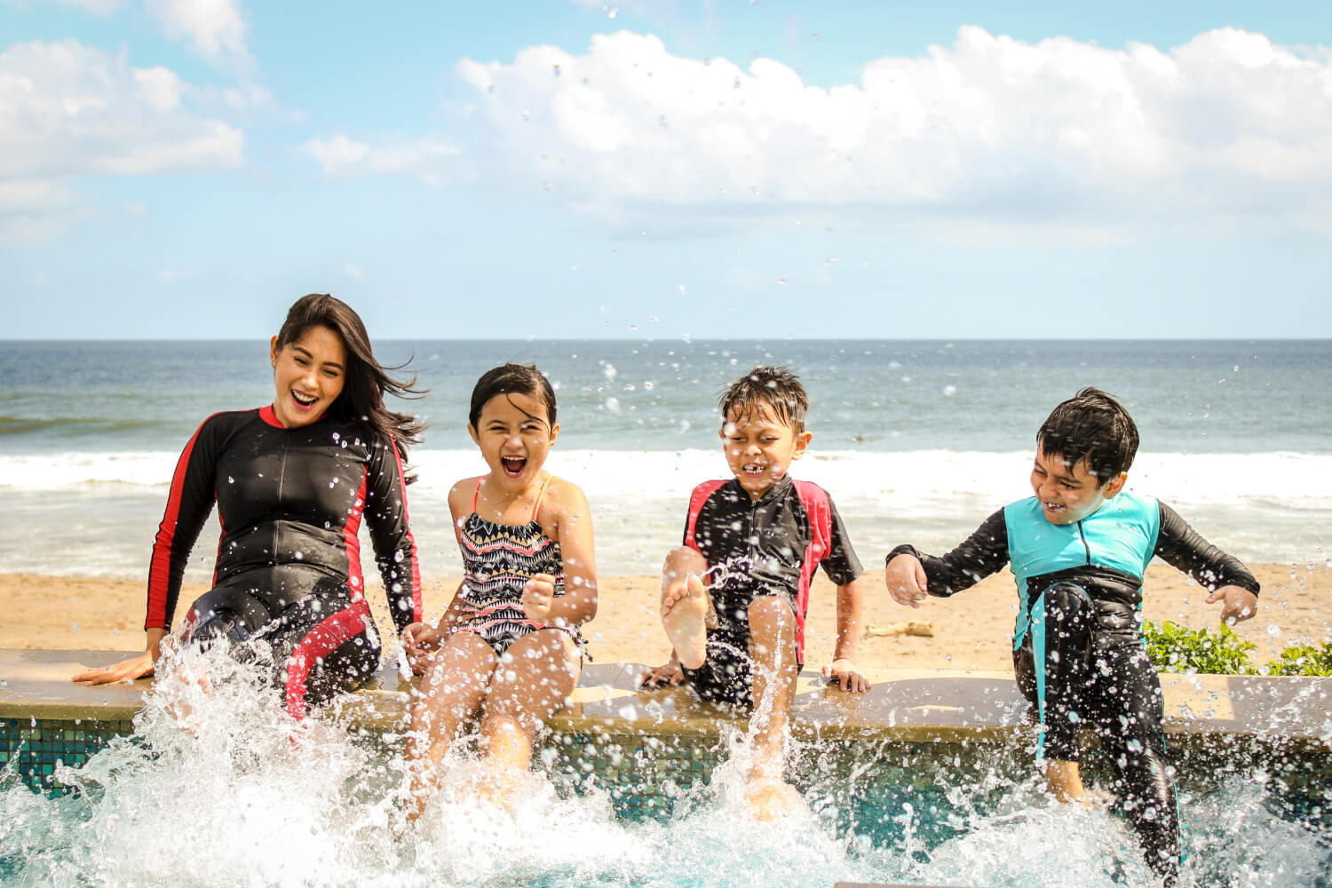 A family sitting on the beach splashing in the water