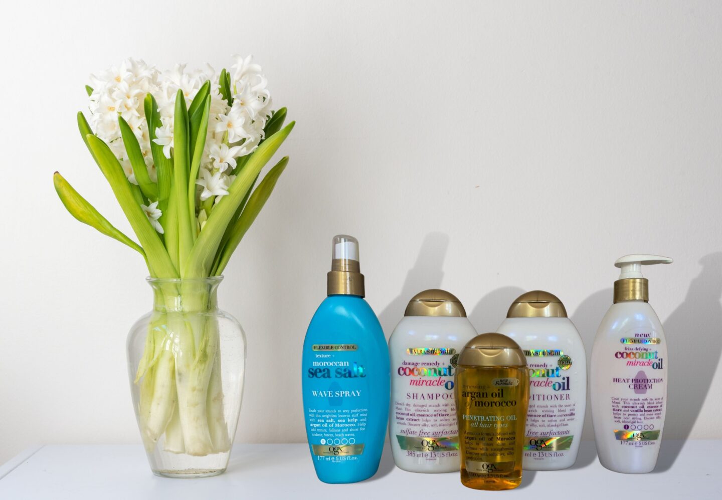 A selection of OGX hair serum, shampoo and conditioners on a bathroom shelf.