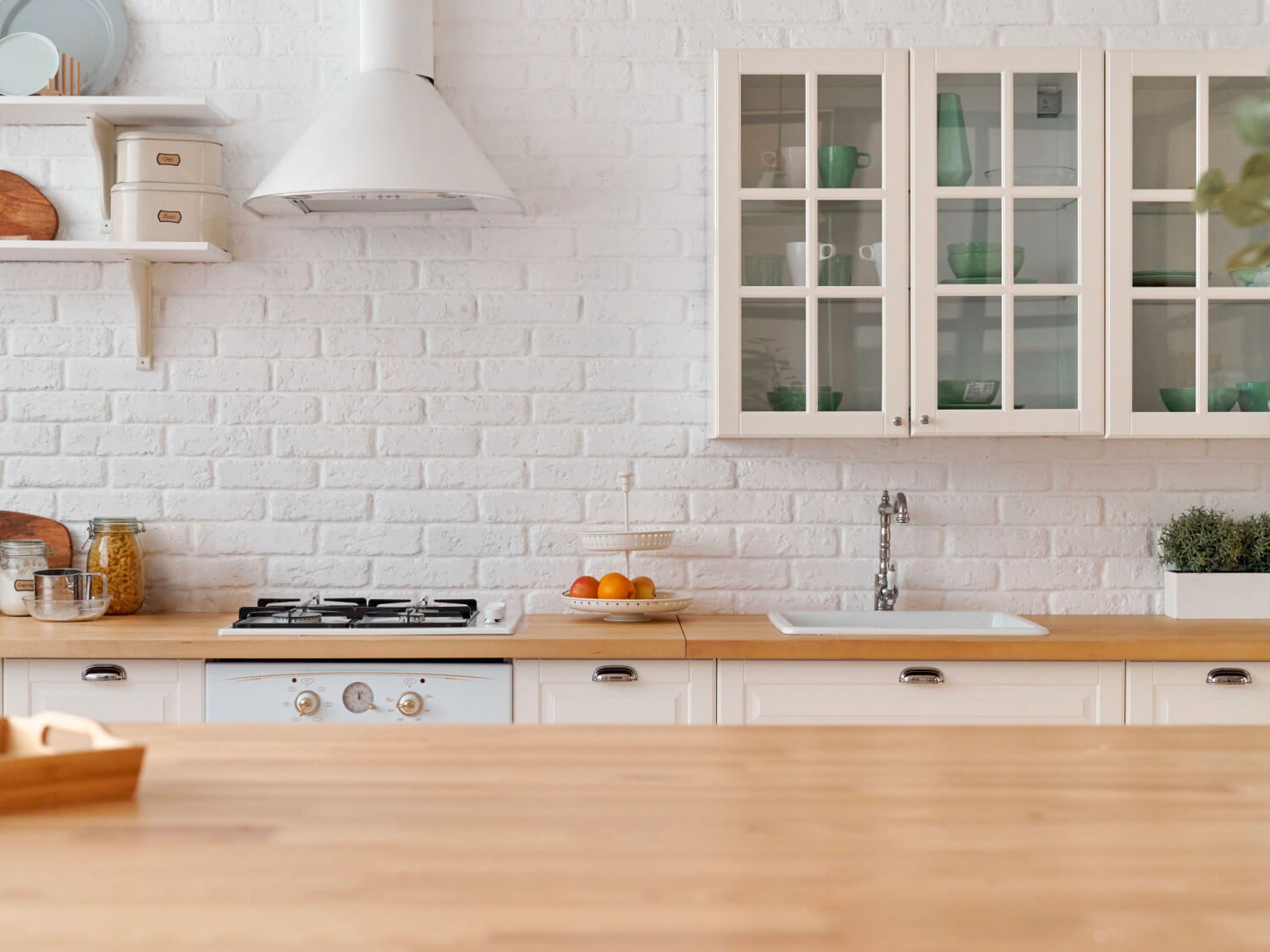 A country style kitchen with thick wooden worktops, white brick wall and Belfast sink.