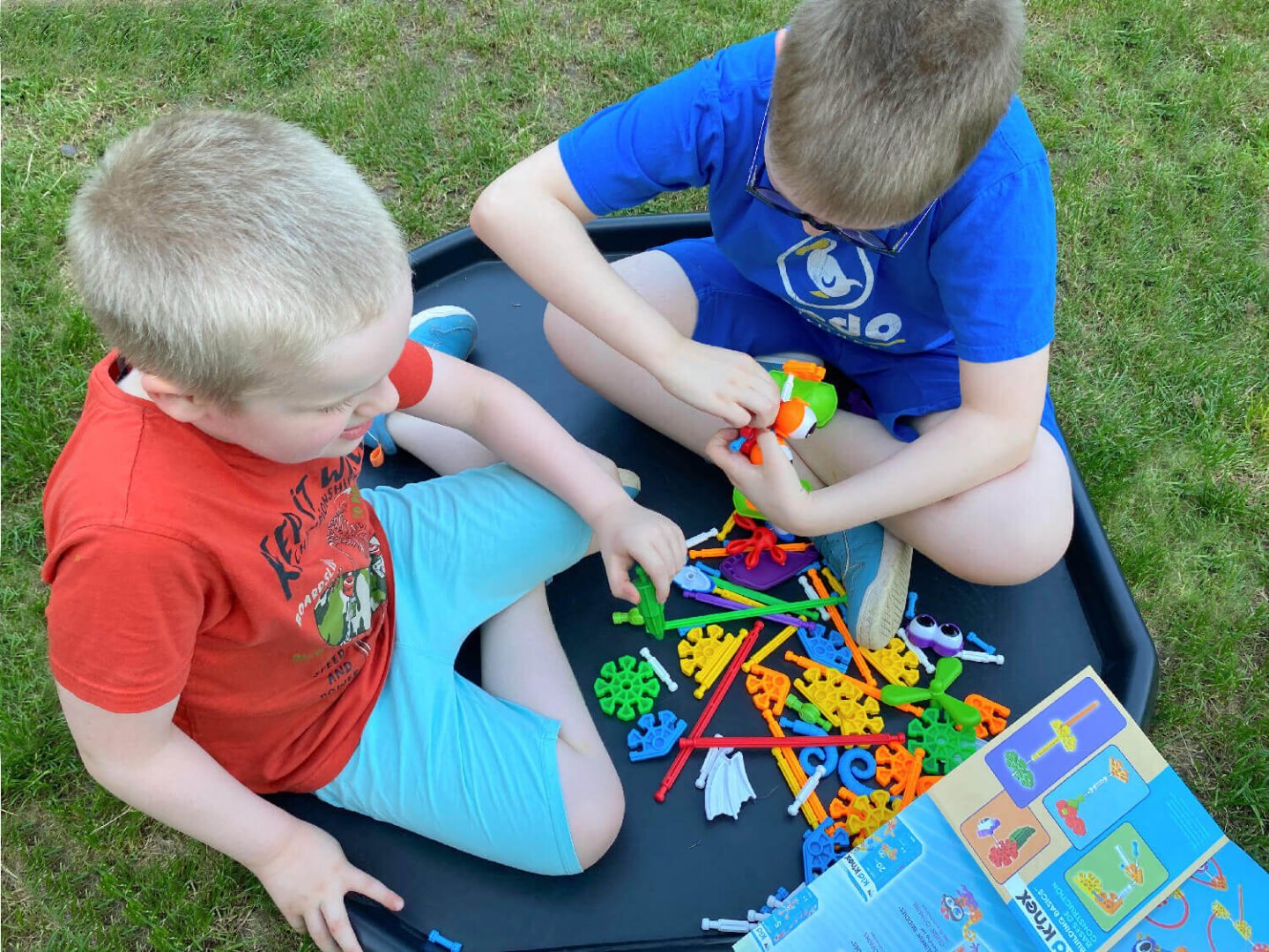 My boys sitting in a tuff tray in the garden building fun characters out of Kid Knex colourful parts.