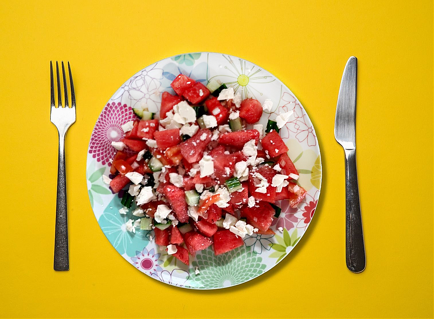 Melon and feta salad on a floral plate with a yellow backdrop