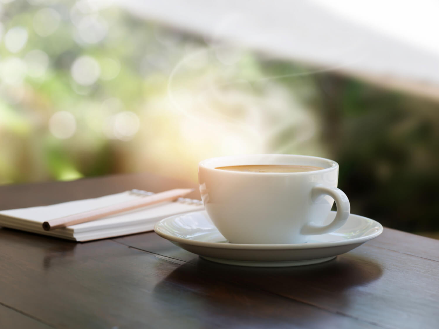 A cup of tea on a table outside with a notebook and pen next to it