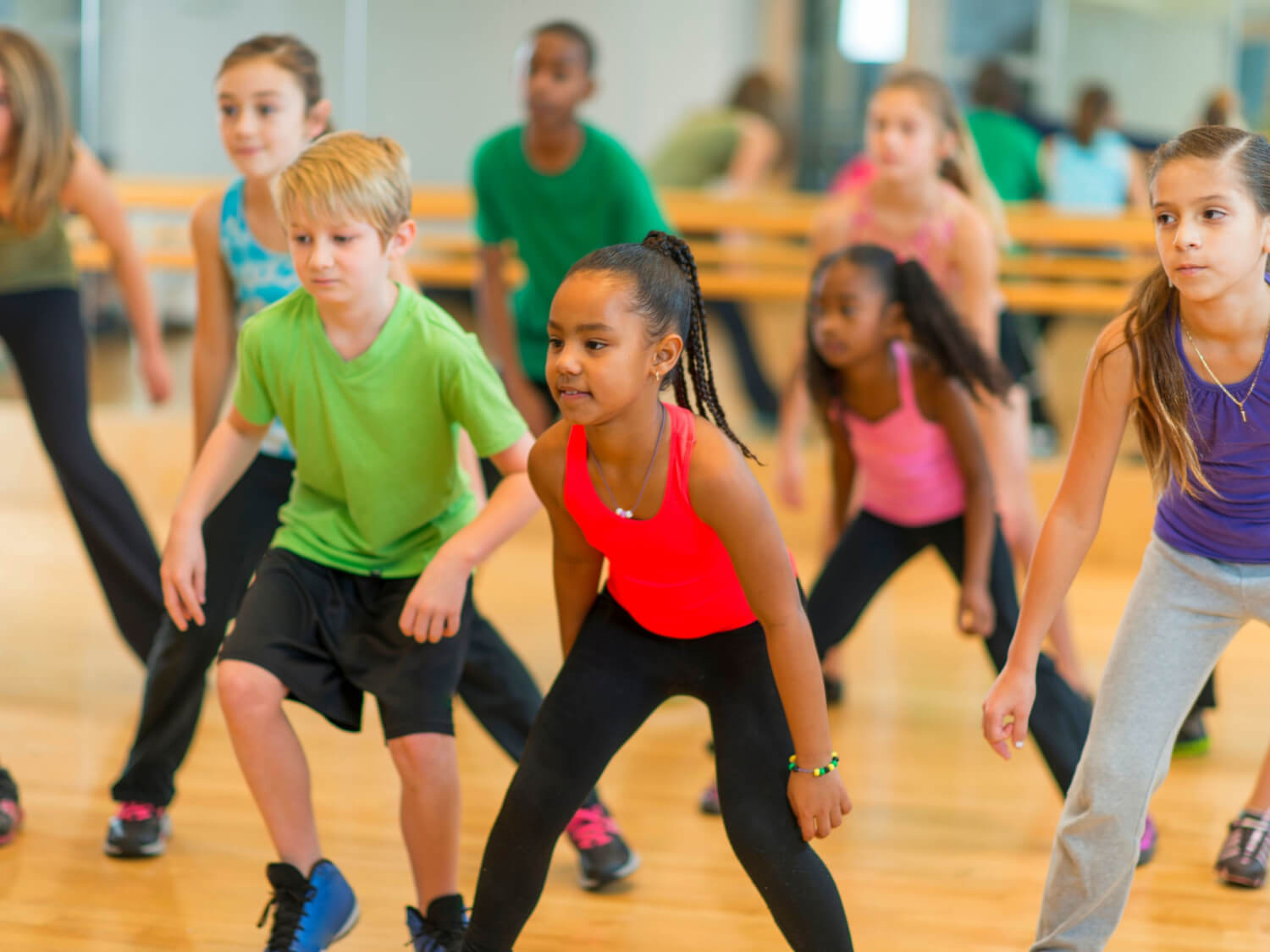 Infant boys and girls being taught dance in a hall