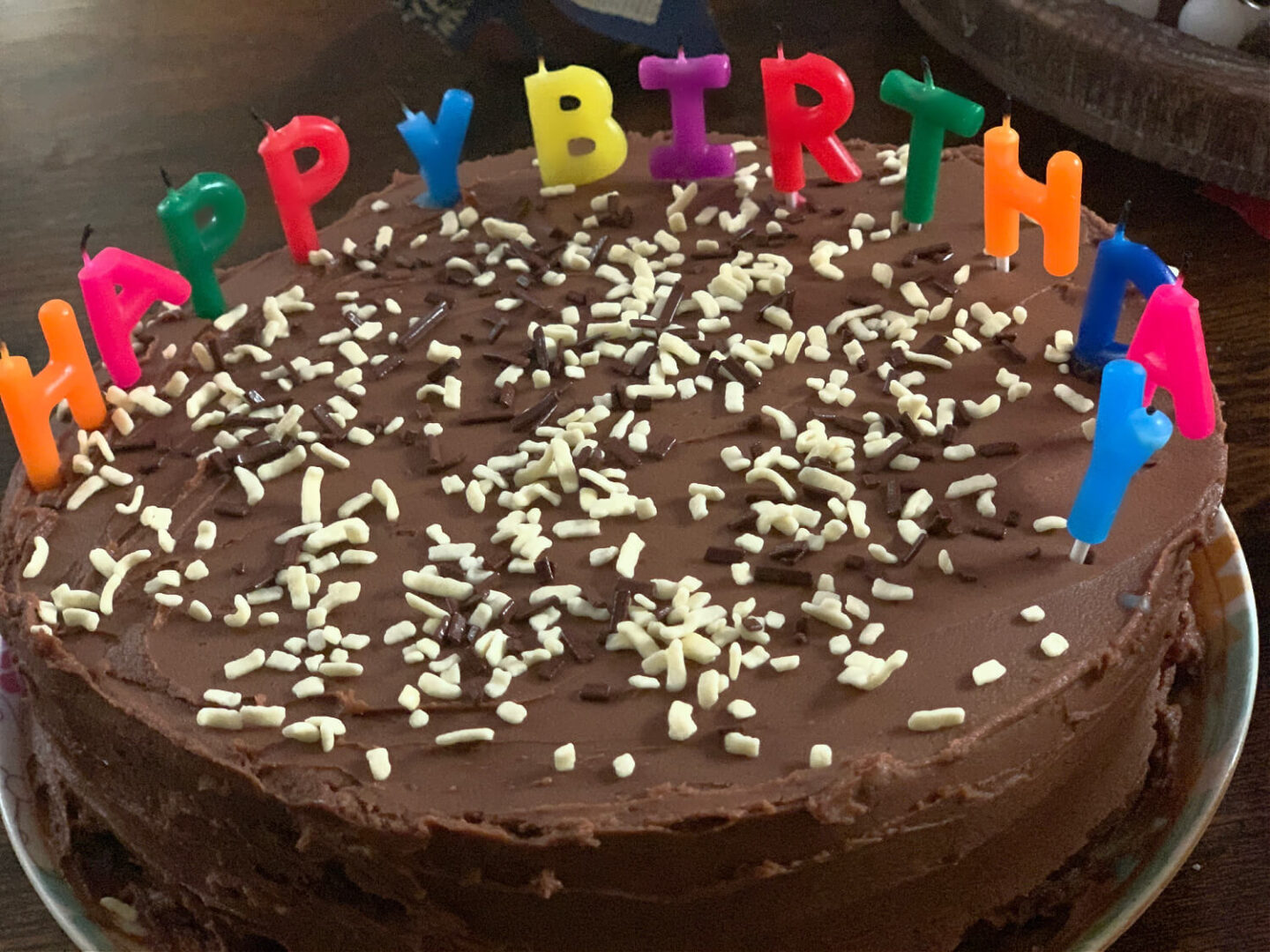 My homemade birthday cake with multicoloured candles that spell Happy Birthday.