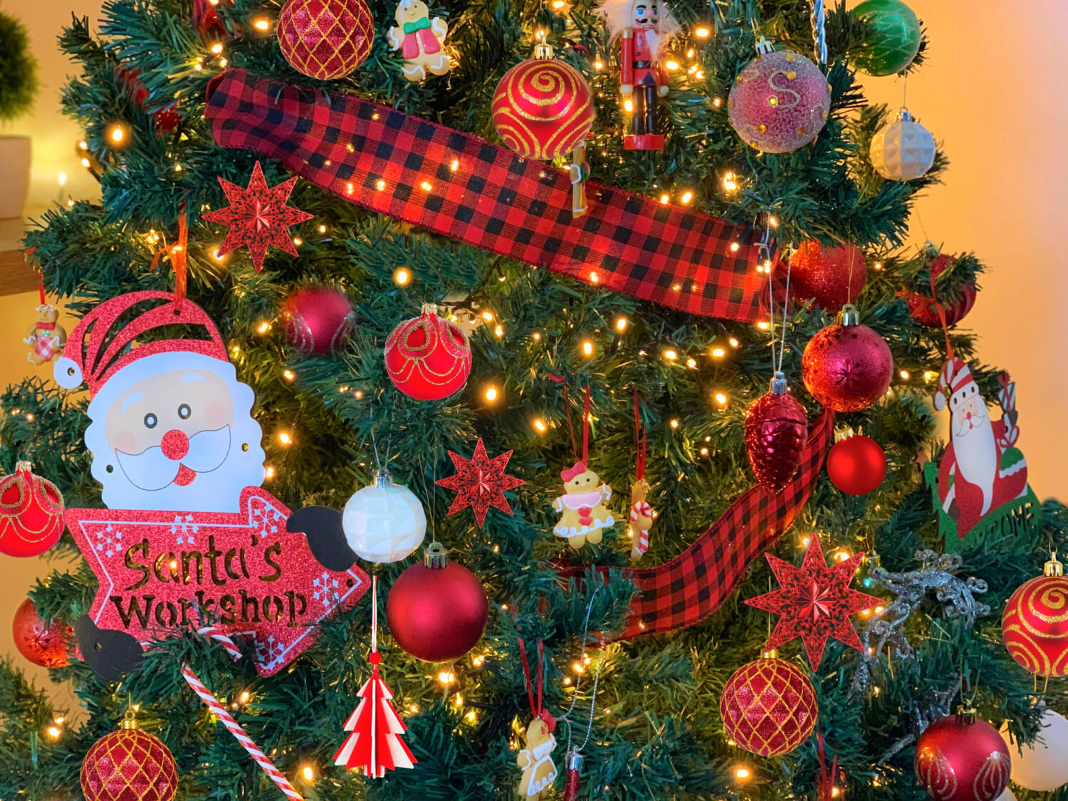 An artifial tree decorated in red and white baubles, gingerbread men, candy canes, buffalo check ribbon and warm white led lights.