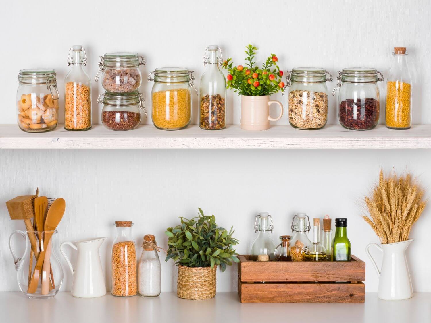 Mason jars filled with cooking ingredients on a white kitchen shelf.