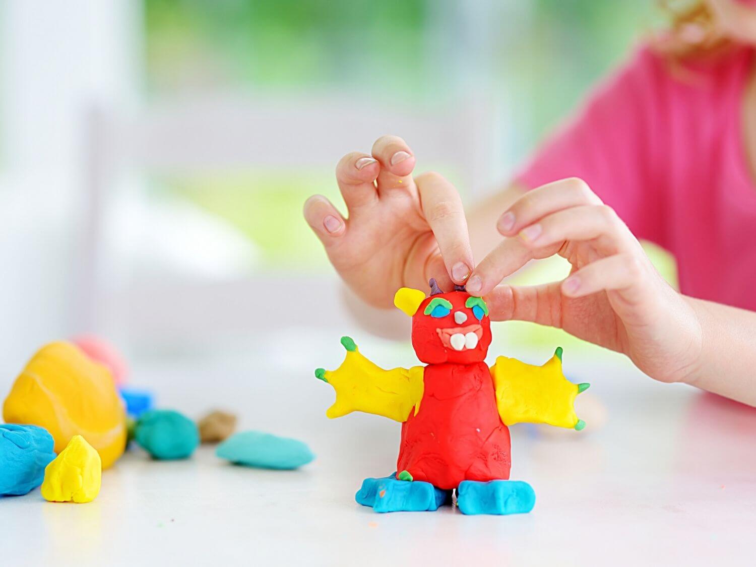 A little girl making a multi-coloured monster out of playdoh.