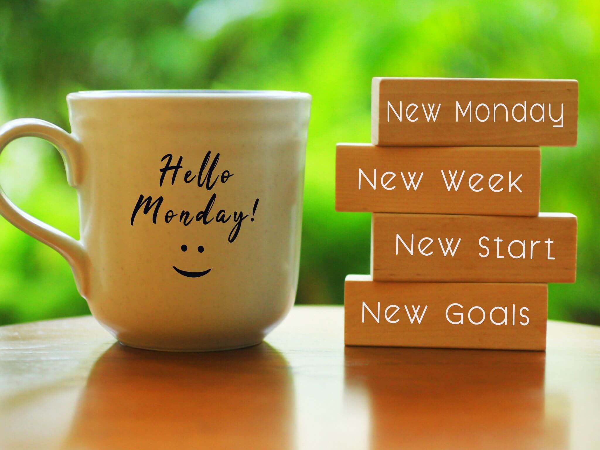 A mug with the words 'Hello Monday' and little wooden blocks stacked up that say "New Monday, new week, new start and new goals.