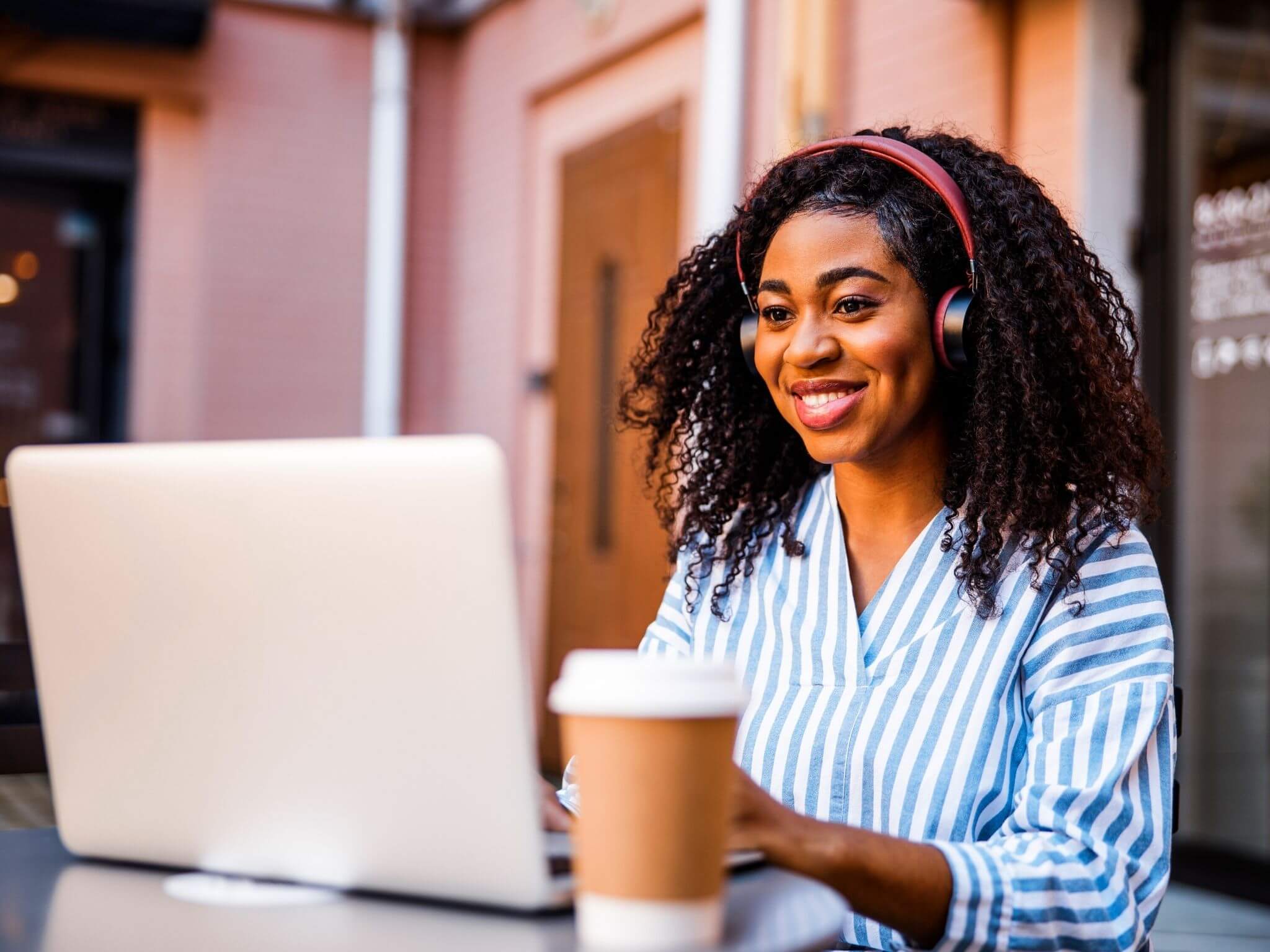 A lady wearing headphones sat working on her laptop