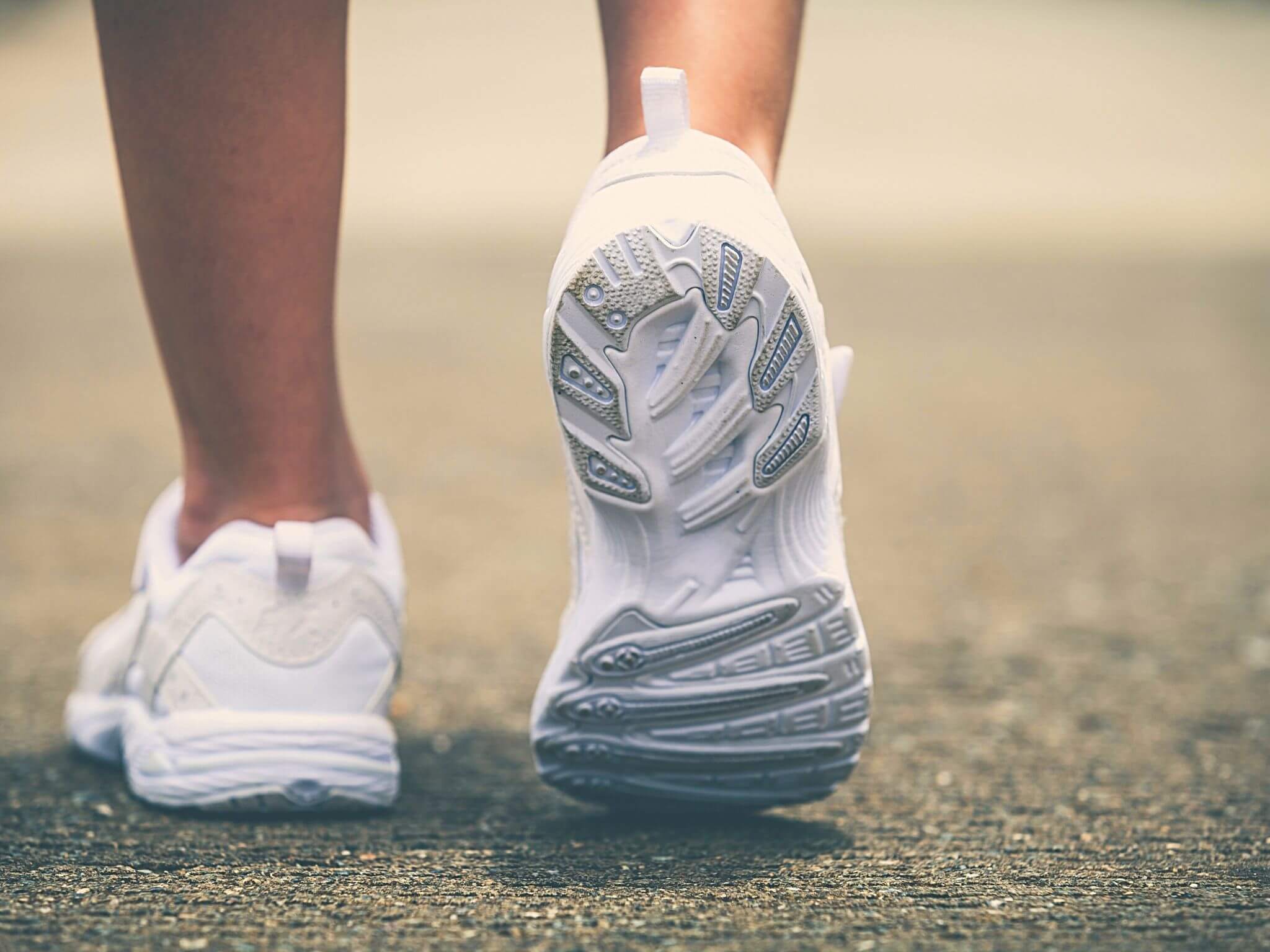 A close up of a lady's white trainers as she walks.
