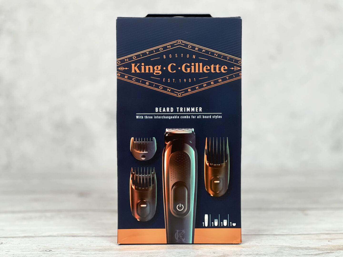 A beard trimmer in a dark navy blue box with gold font