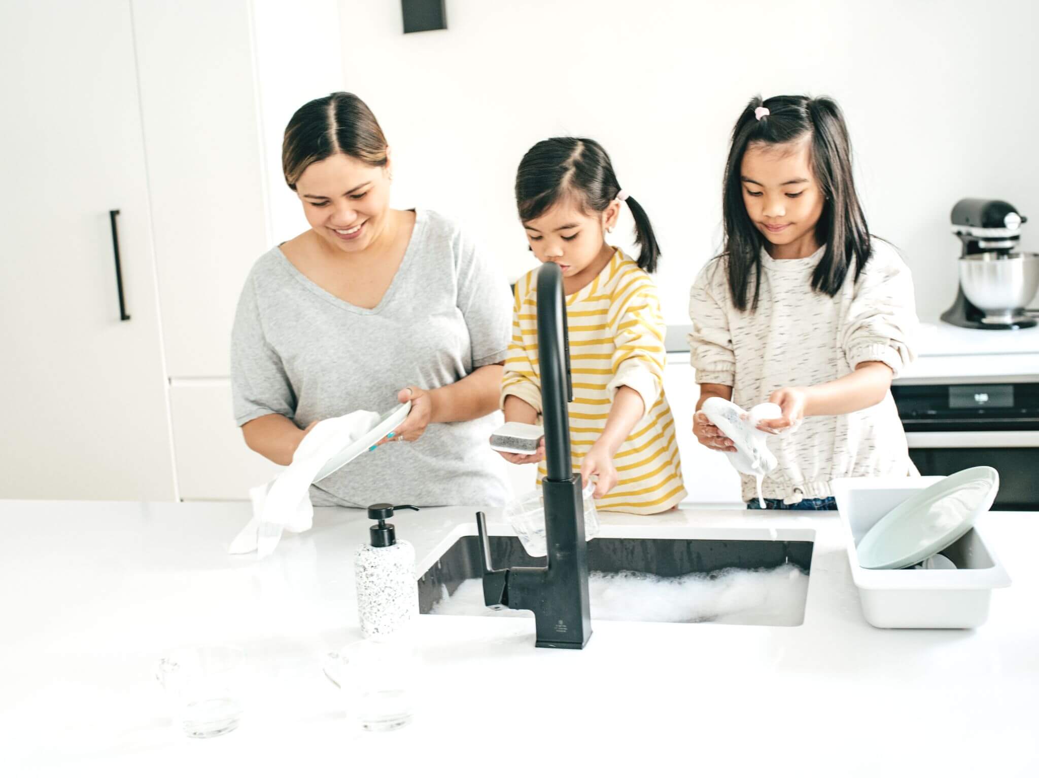 Young sisters helping their mum wash up.