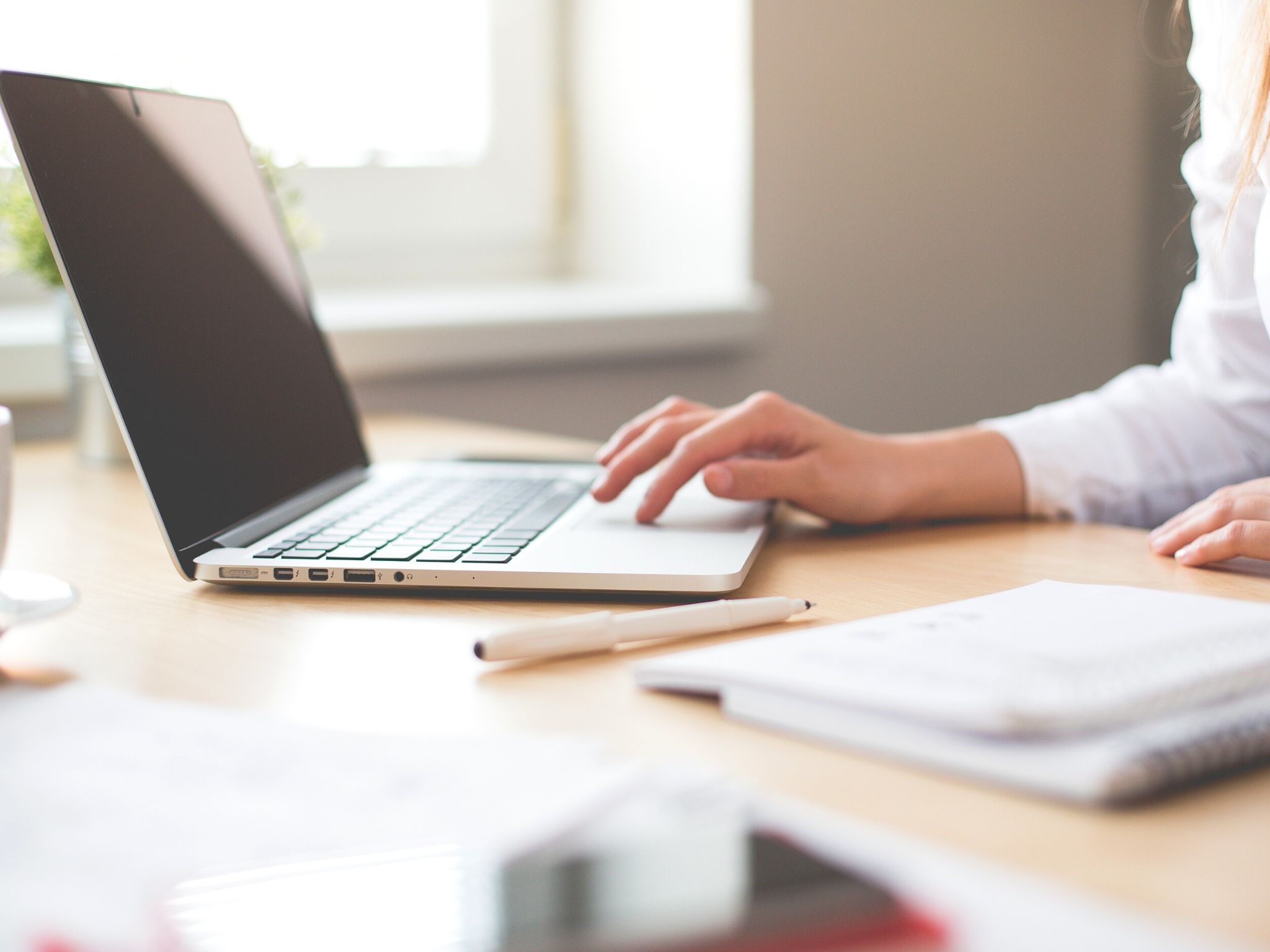 A lady working on her laptop at a desk.