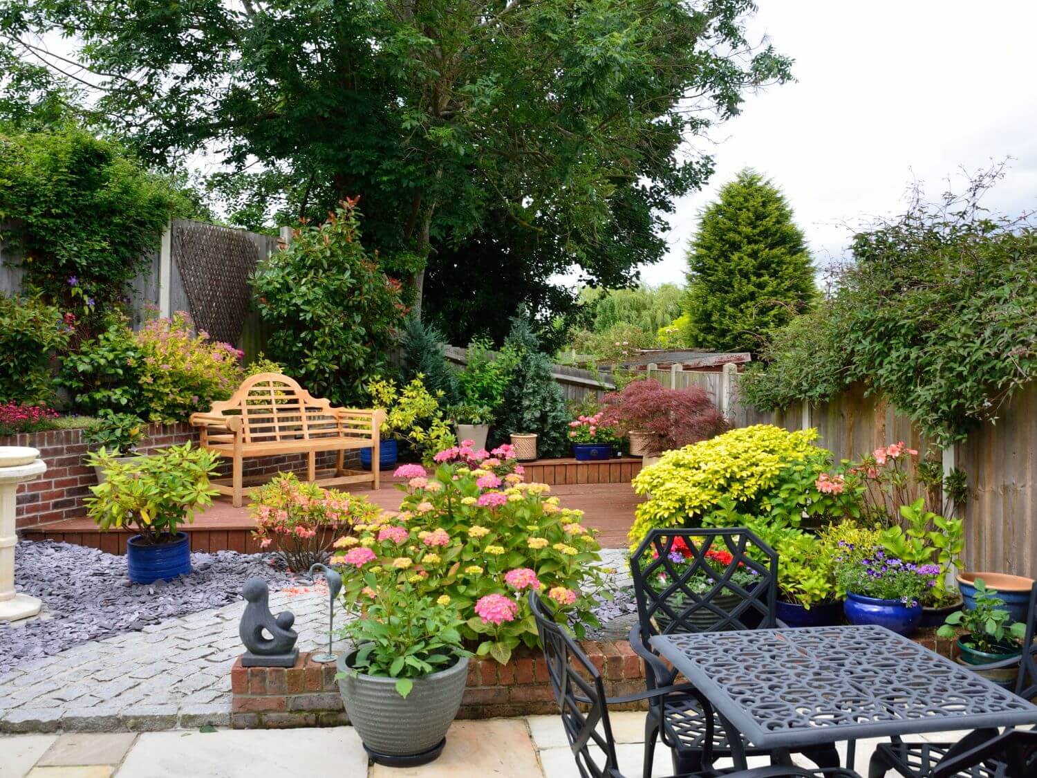 A small garden broken up into little areas. There is a patio, a wildlife corner and a bench area.