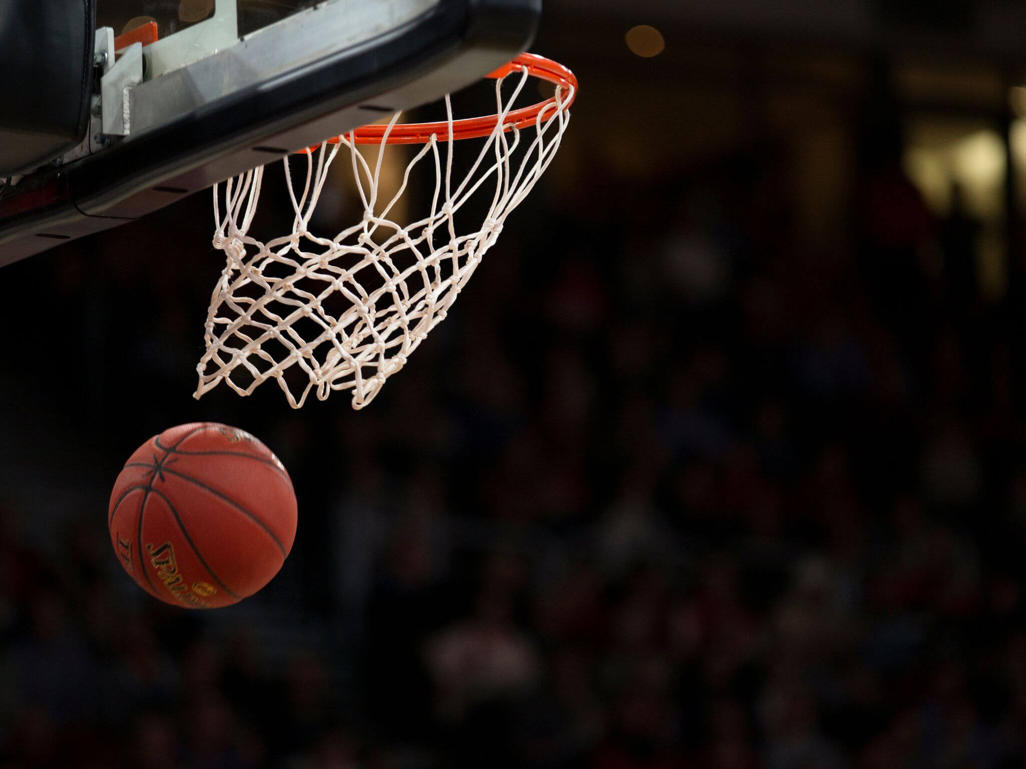 A close up of a basketball hoop and the basketball just passing through.