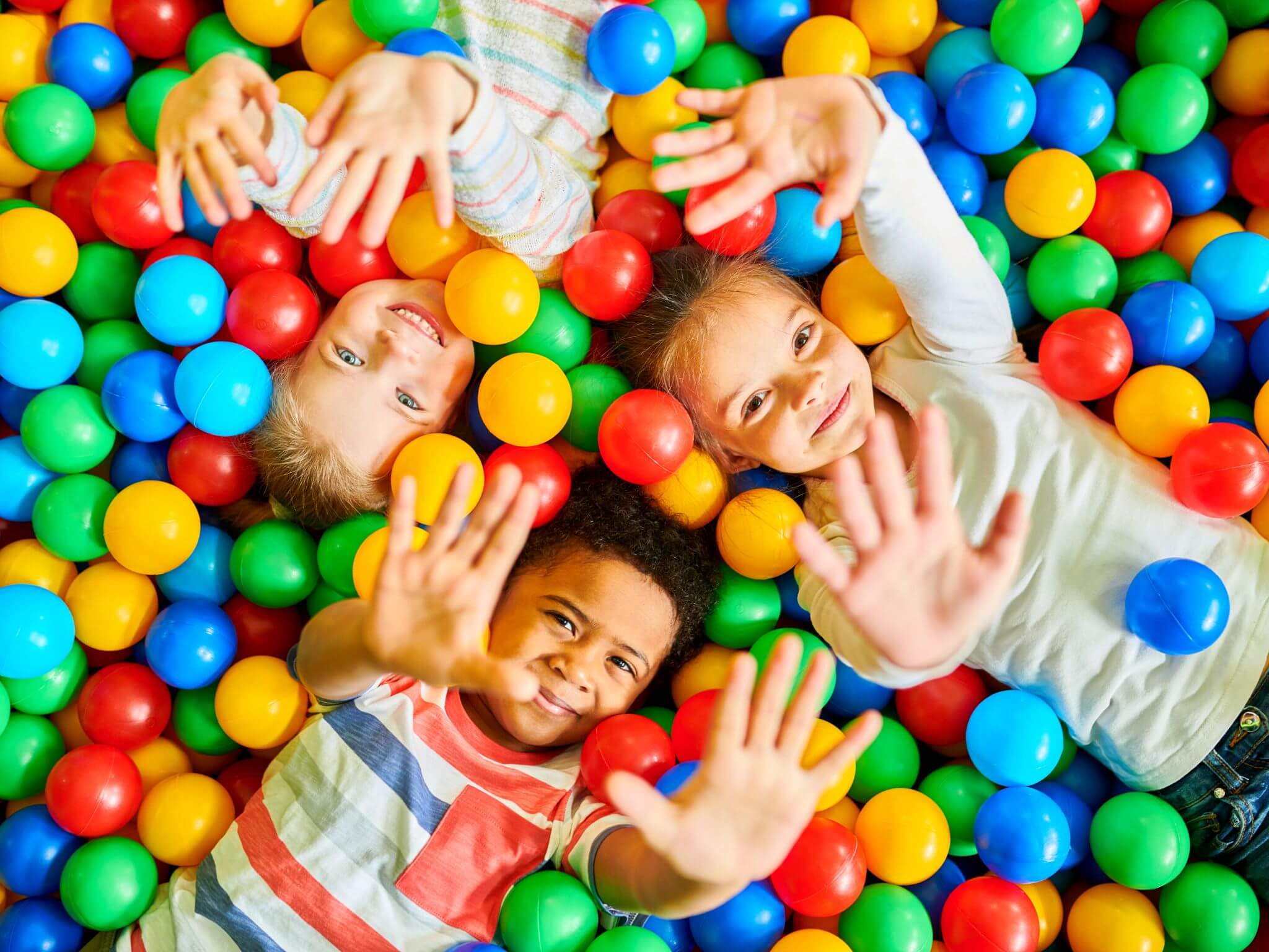 Three kids playing in a ball pit.