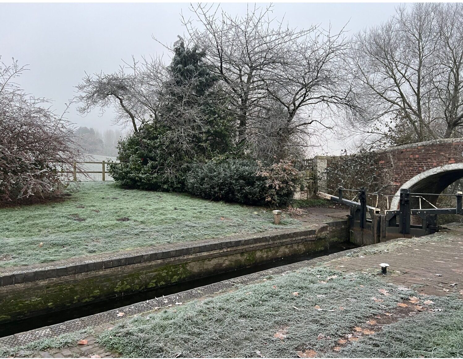 A photo of the morning frost on the canal lock outside our home. You can see the old brick bridge to the right and the fields straight ahead.
