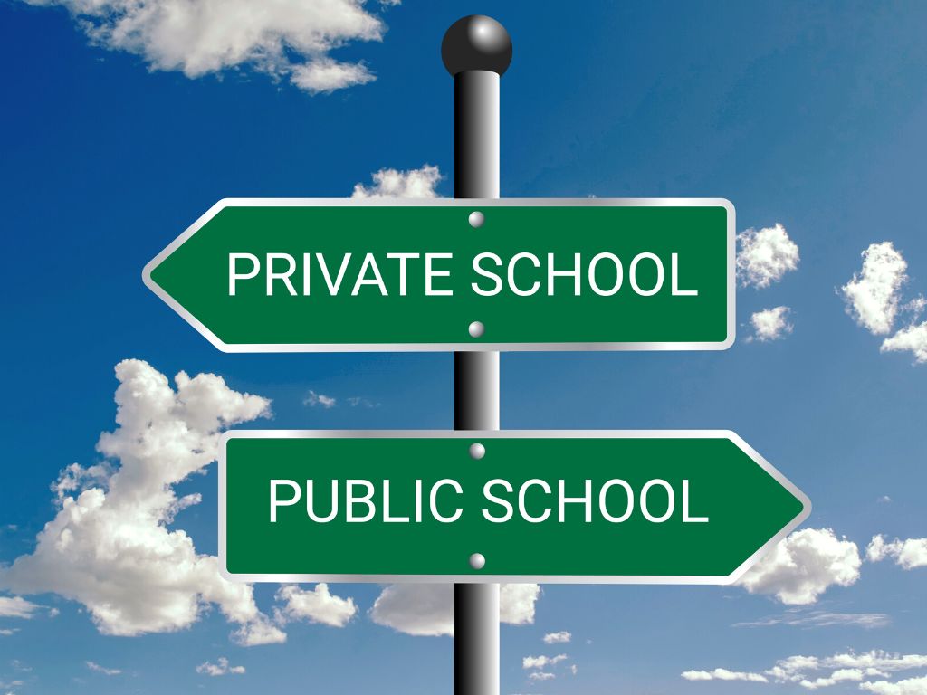 Two arrow signs on a pole pointing in different directions. One reads 'Private school' the other reads 'public school'.
